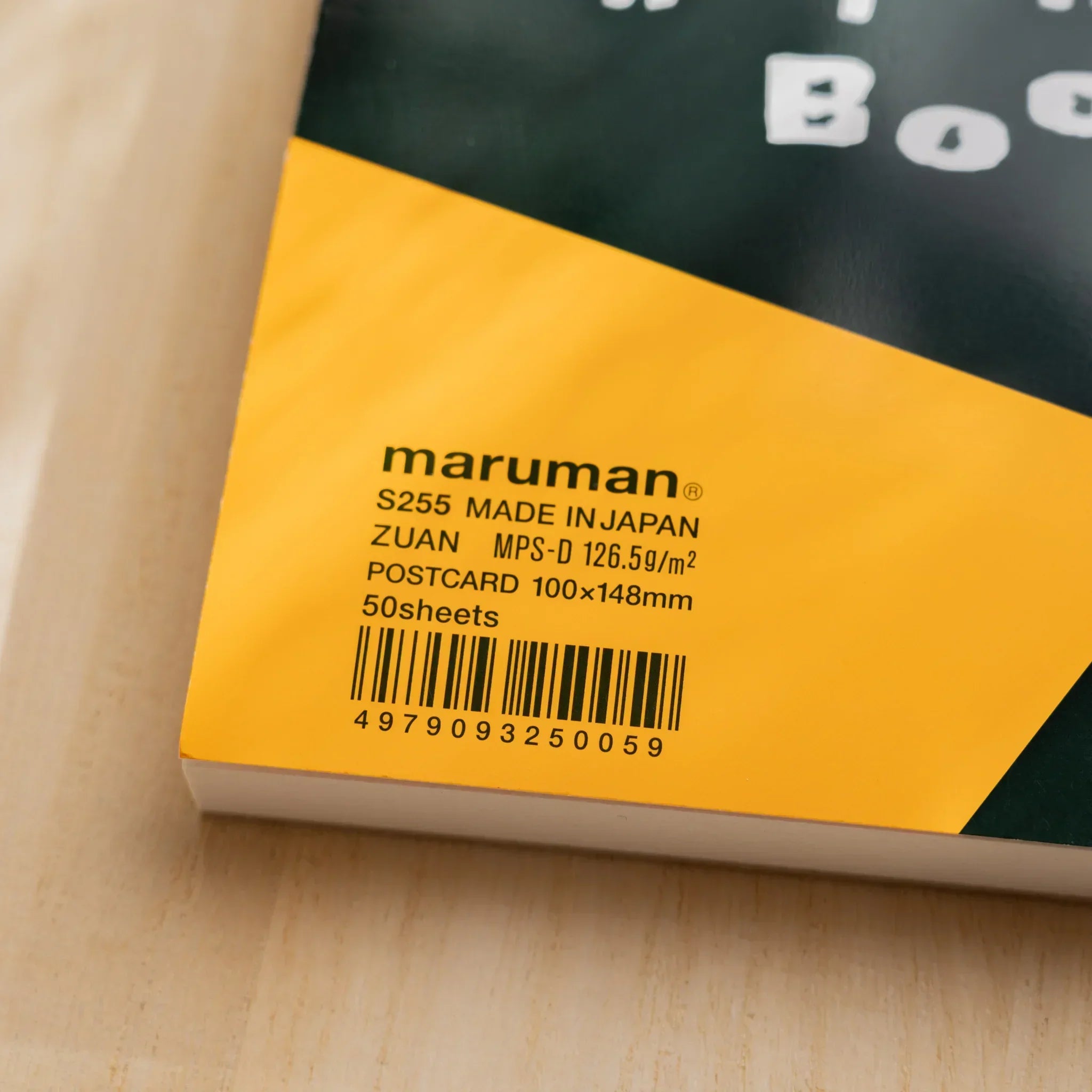 Detail of Maruman Japanese sketchbook orange cover showing printed product information, barcode, and black geometric design.
