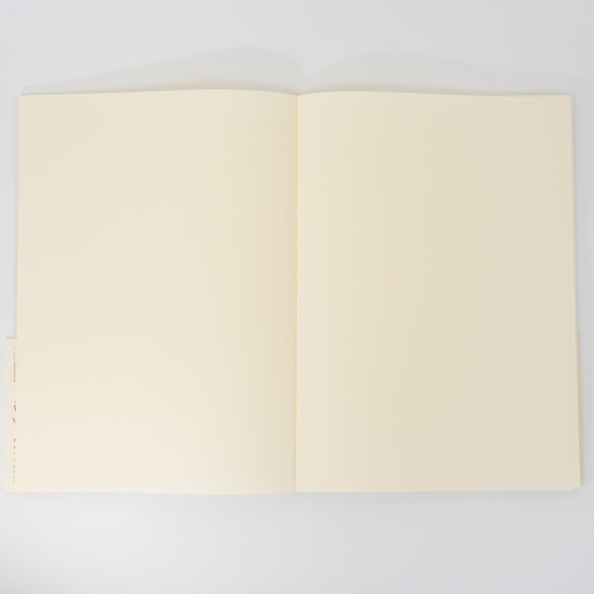 An open Japanese stationery MD Notebook reveals its smooth, blank cream-colored pages, perfect for sketching, journaling, or creative writing.