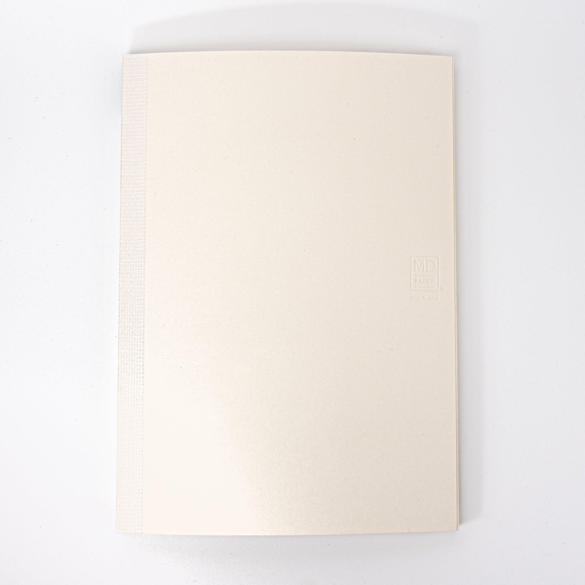 The back cover of a Japanese stationery MD Notebook features an embossed logo on a plain beige design, emphasizing its simple and elegant style.