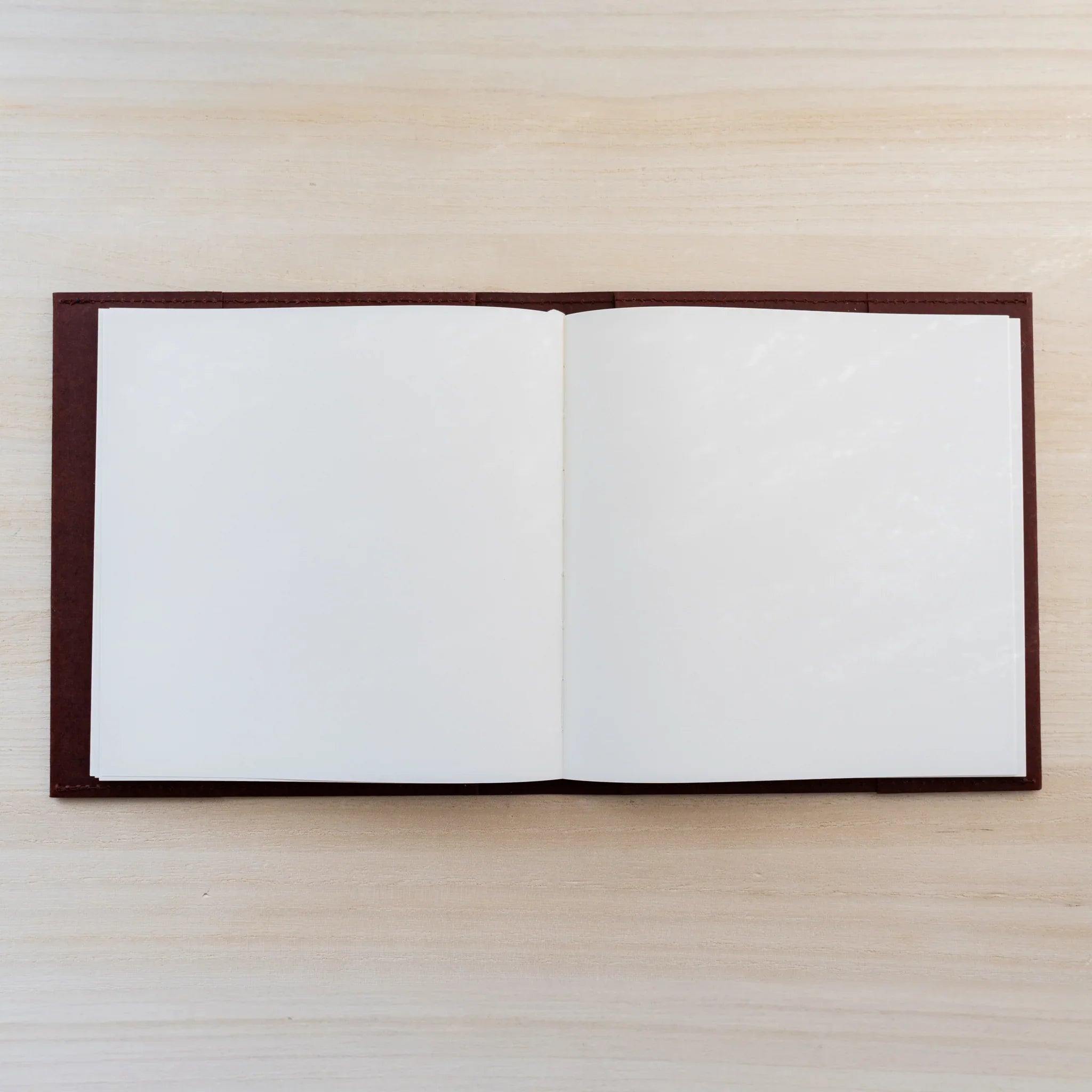 Notebook inside the dark maroon MD Notebook Hard Cover A5 Square, open blank white square spread