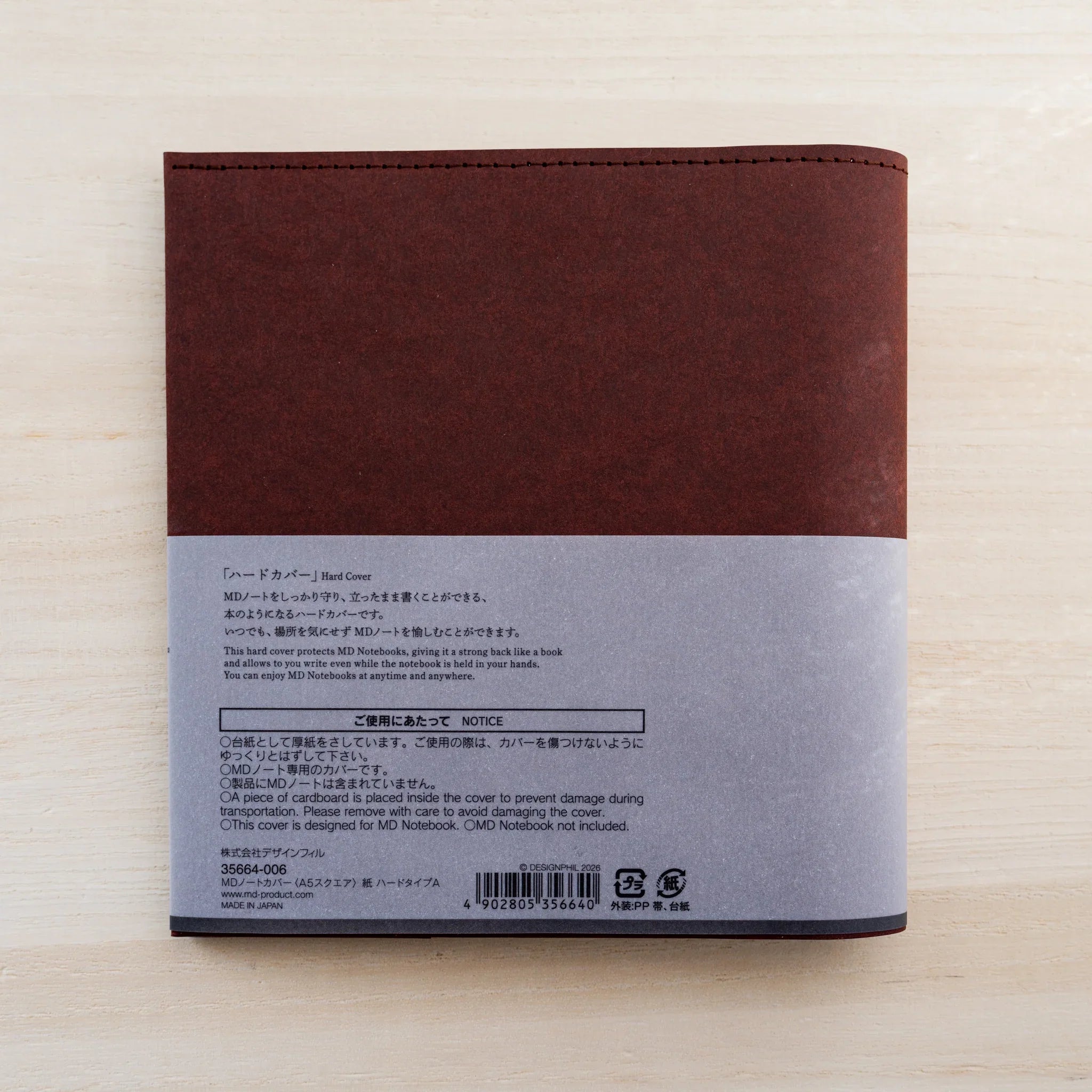 Back of the dark maroon MD Notebook Hard Cover A5 Square with grey belly band, notice text and barcode
