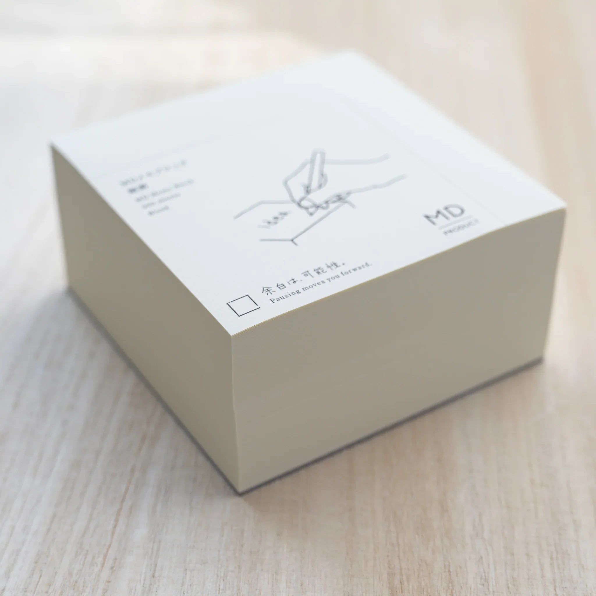 Angled MD Memo Block with white wrap showing a line illustration of a hand writing idea and MD Product logo