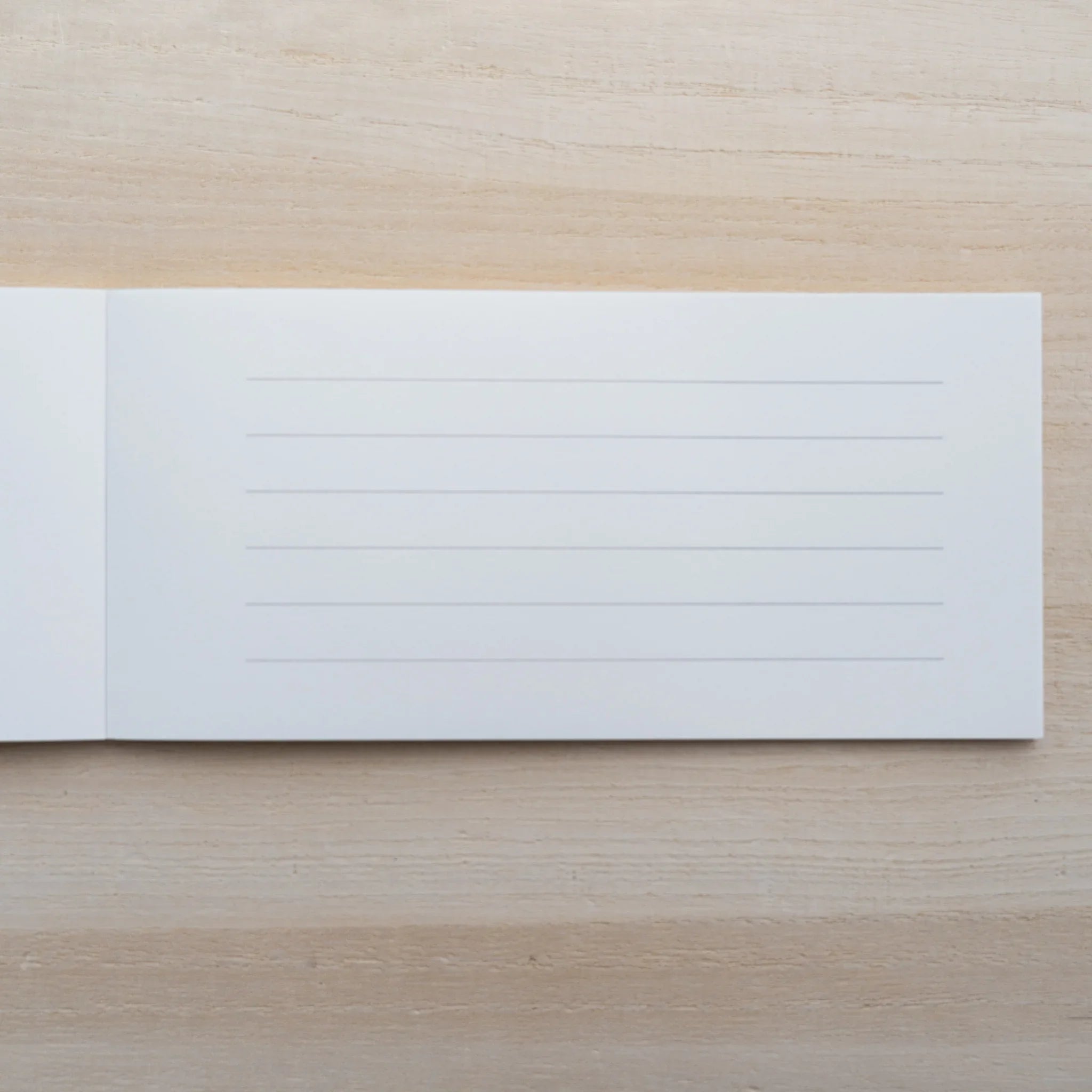MD Paper Cotton letter pad opened to a sheet with faint ruled lines on cream paper, on a wood surface