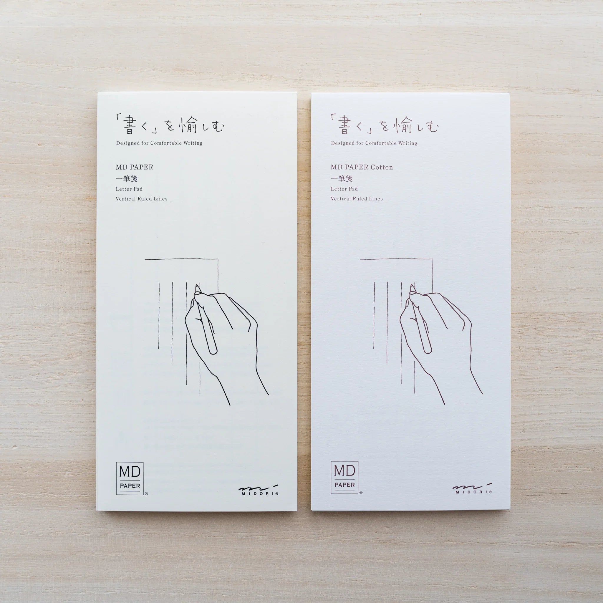 MD Paper and MD Paper Cotton letter pads side by side, both reading Letter Pad Vertical Ruled Lines with hand illustration