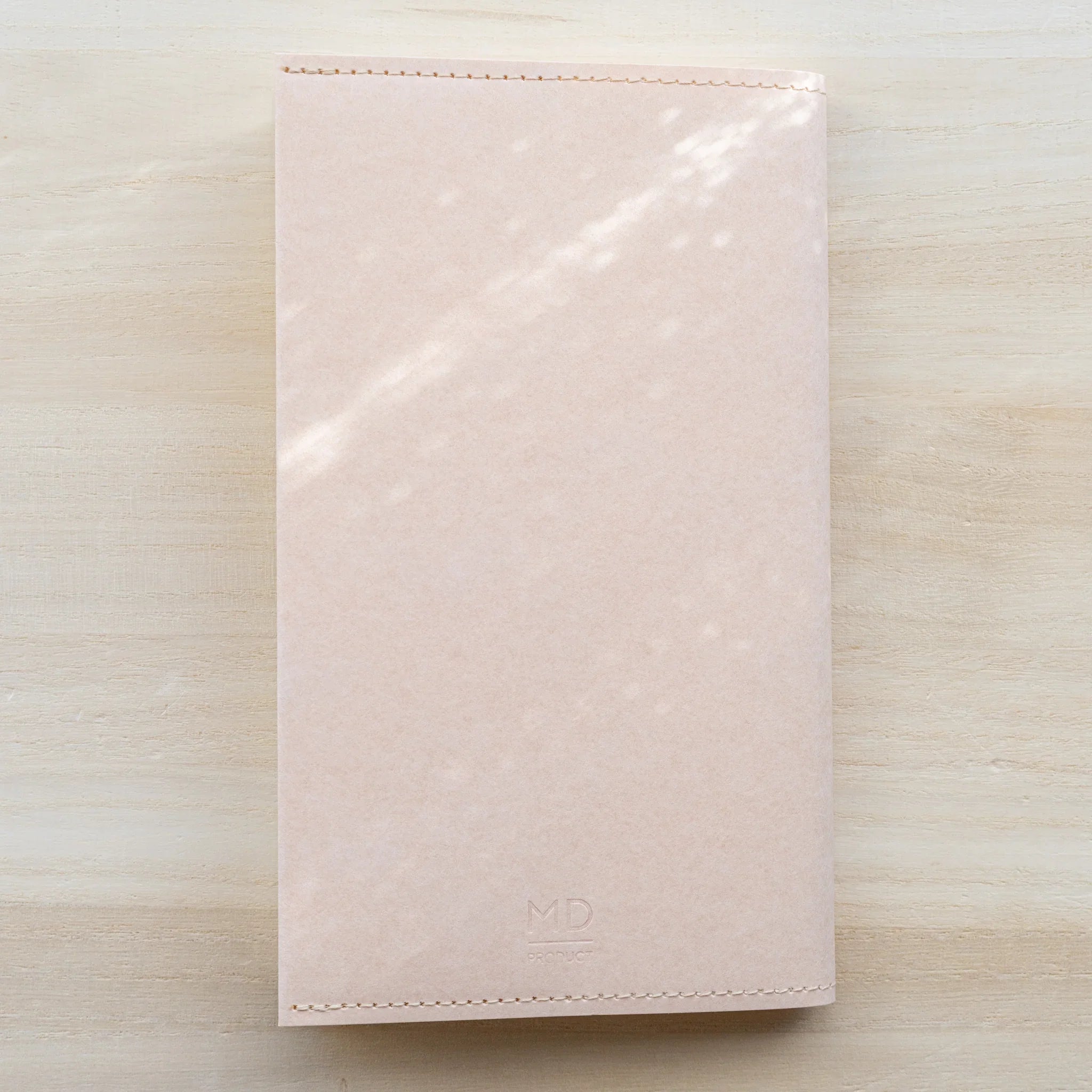 Front view of MD Product Paper Notebook Cover B6 Slim in peach kraft paper with embossed MD logo.