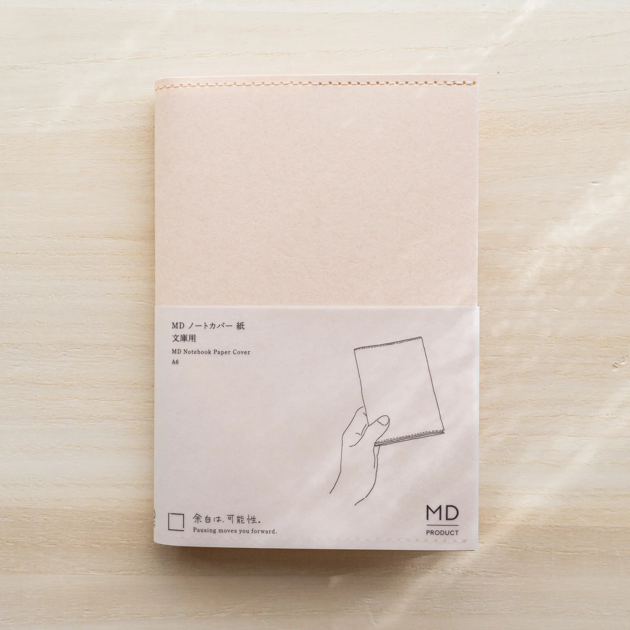 MD Notebook Paper Cover A6 in pale pink paper with belly band and hand-with-notebook line drawing