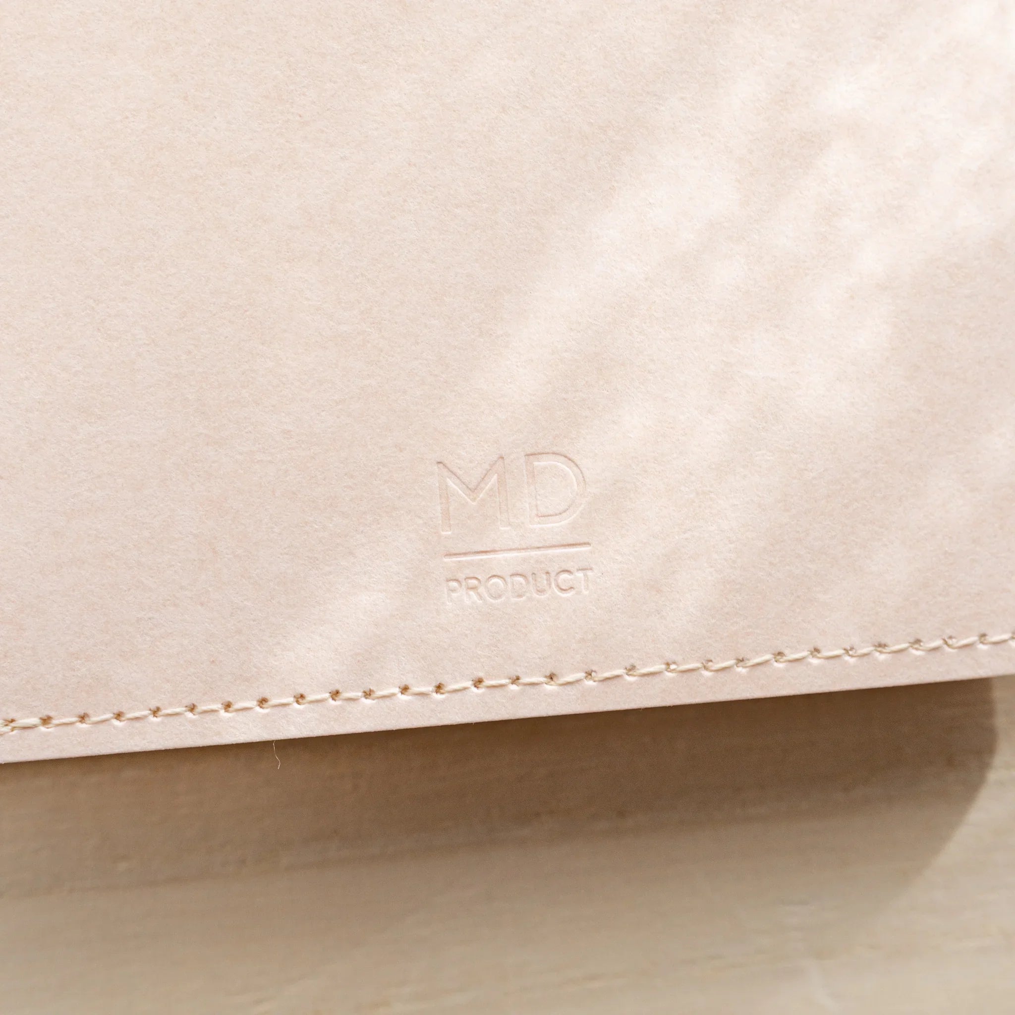 Close-up of a pale pink MD Notebook Paper Cover edge showing the fold and stitching holes
