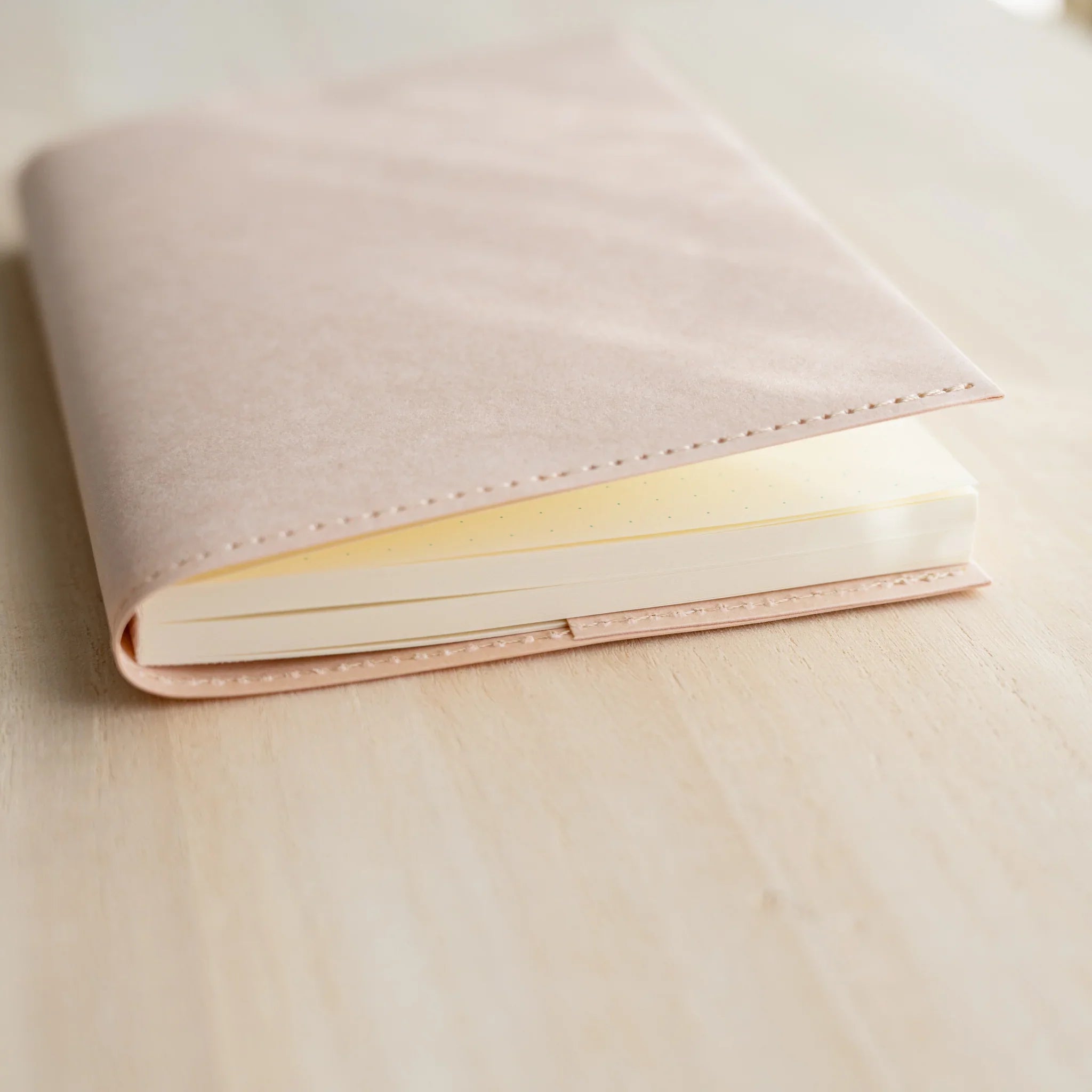 Side view of MD Paper Notebook Cover with notebook, showing pale paper spine, ivory page edges, and blue ribbon bookmark