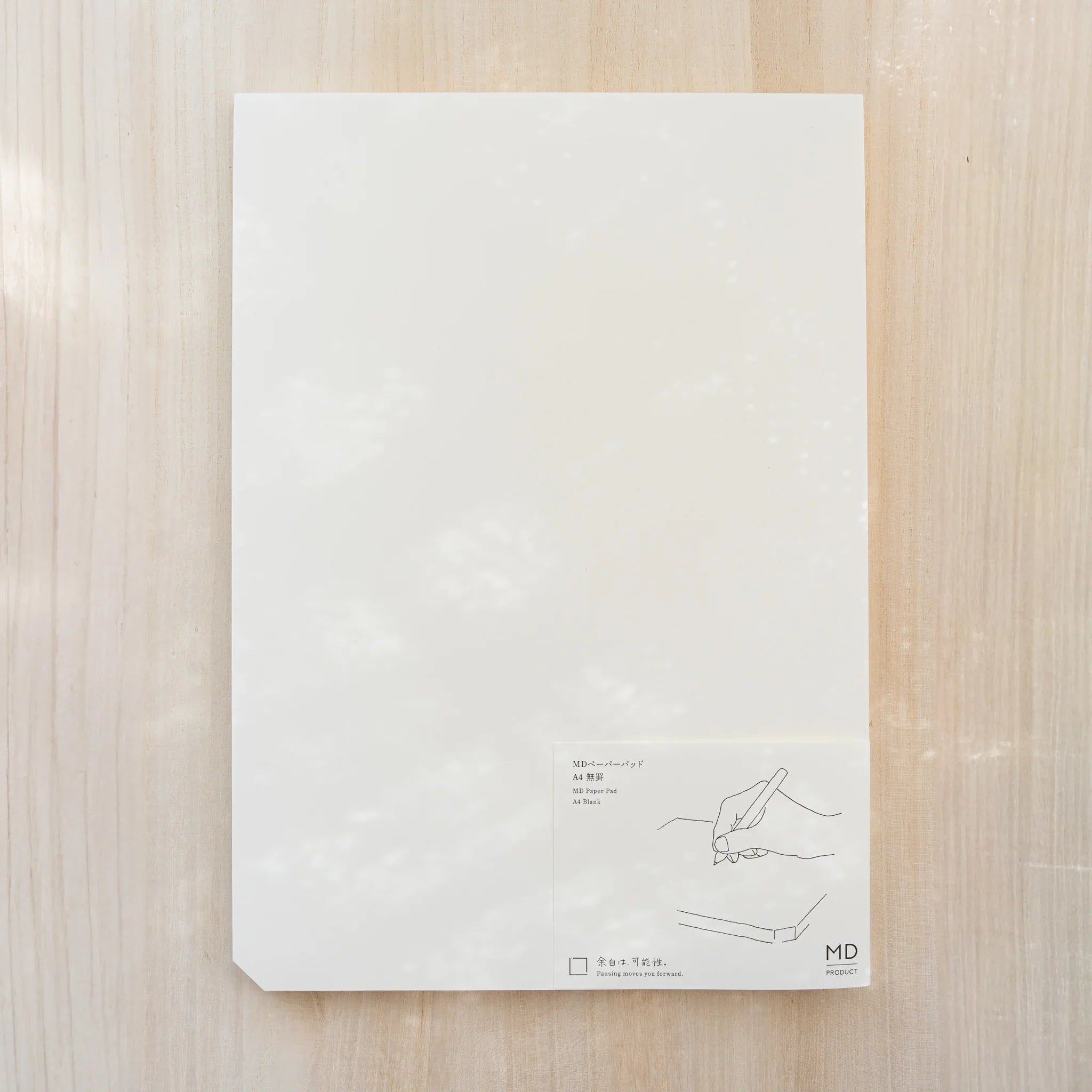 Midori MD Paper Pad A4, white top sheet with paper belly band reading MD Paper Pad A4 Blank and hand drawing