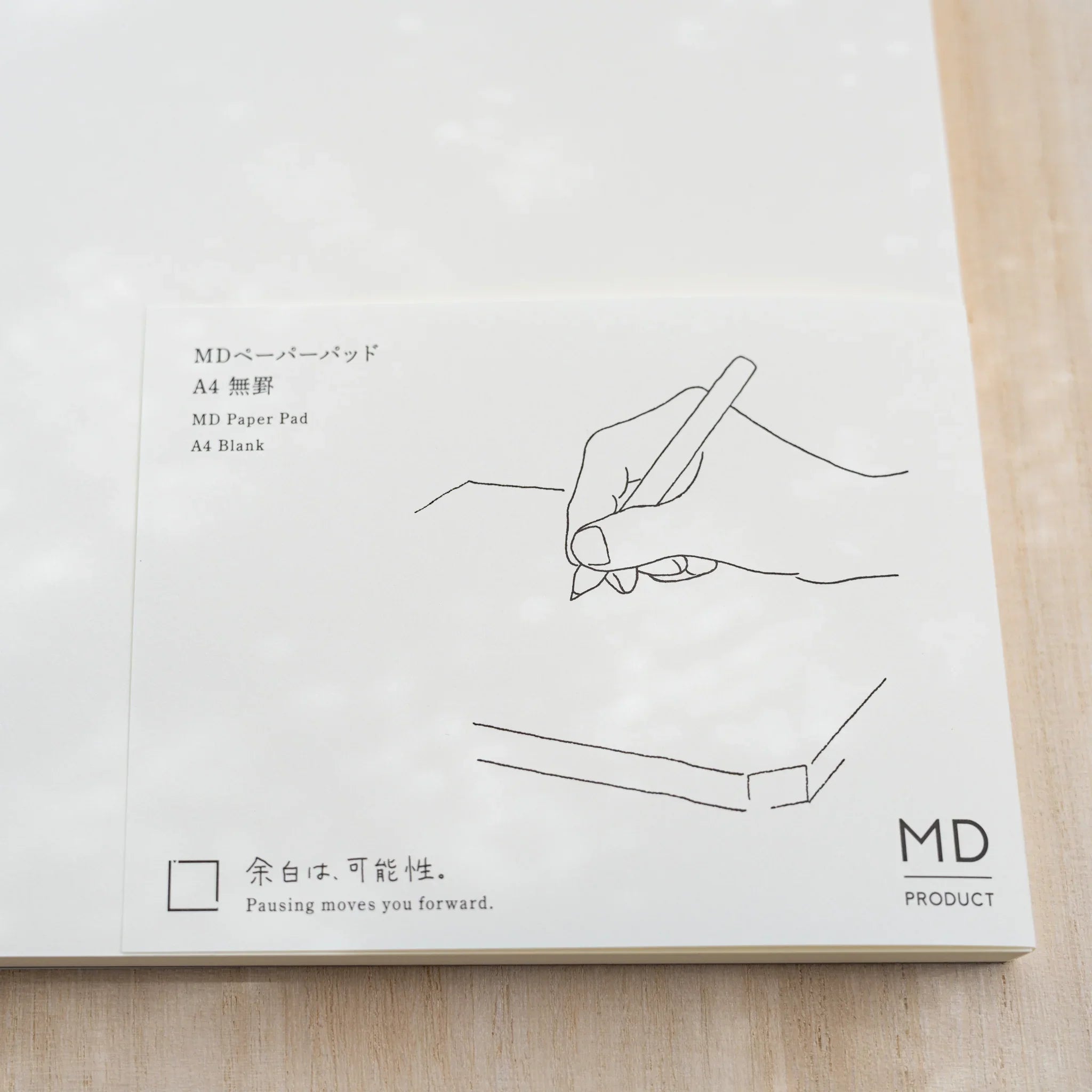 Close-up of Midori MD Paper Pad A4 paper belly band, hand-writing line drawing and text MD Paper Pad A4 Blank