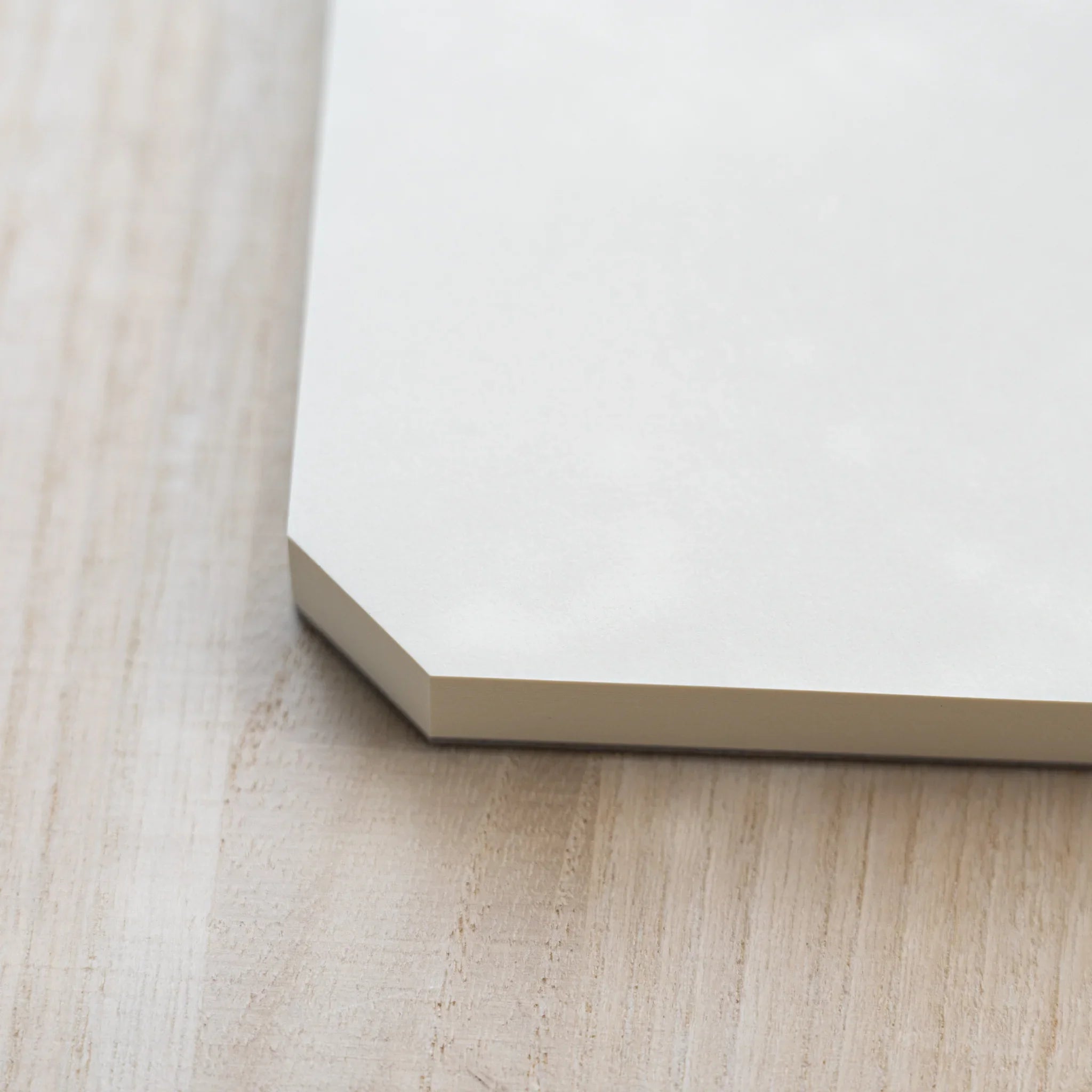 Close-up of the angled cut corner of a Midori MD Paper Pad A4 with page block on a gray backing board
