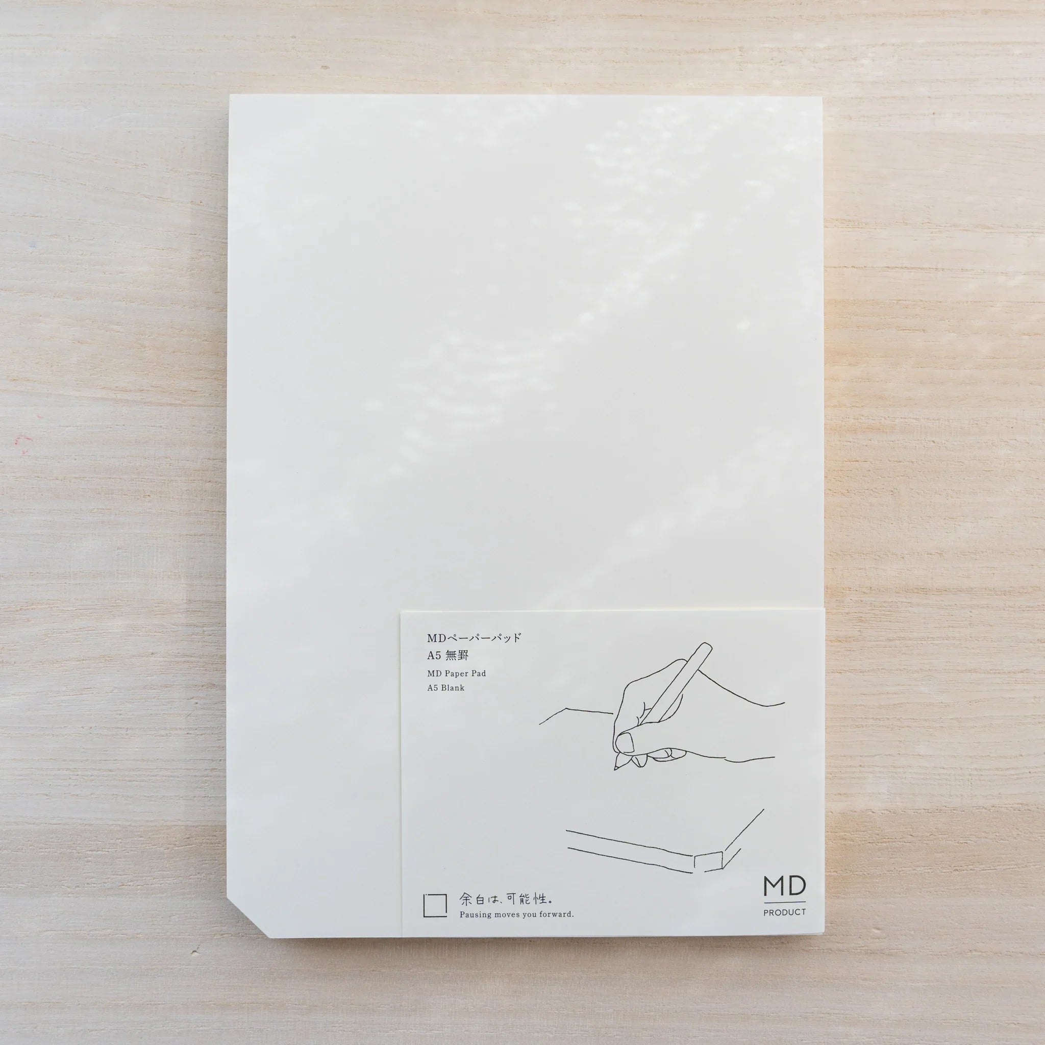 Midori MD Paper Pad A5, white top sheet with paper belly band reading MD Paper Pad A5 Blank and hand-writing line drawing