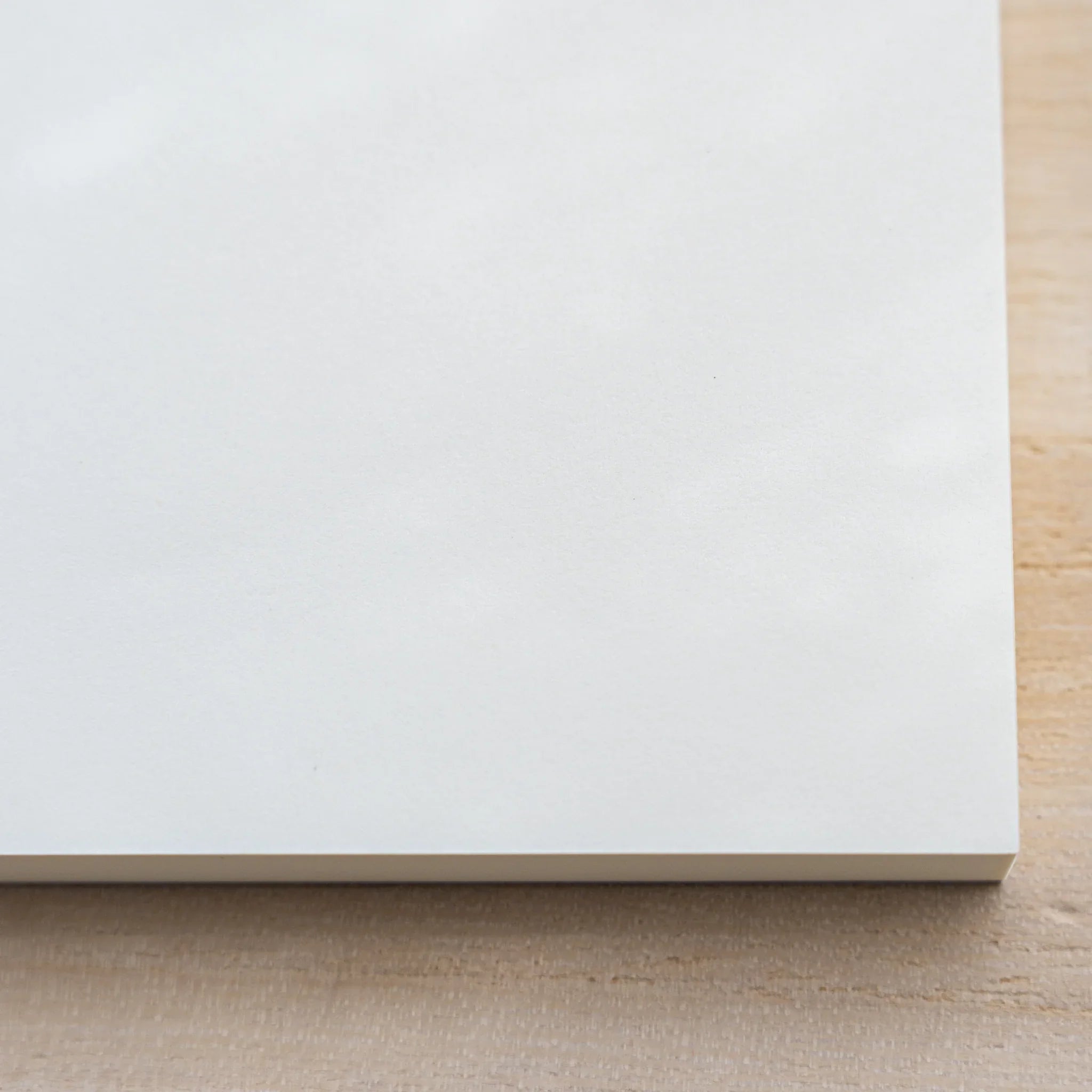 Close-up of Midori MD Paper Pad A5 lower edge showing the cream top sheet and thin glued page block