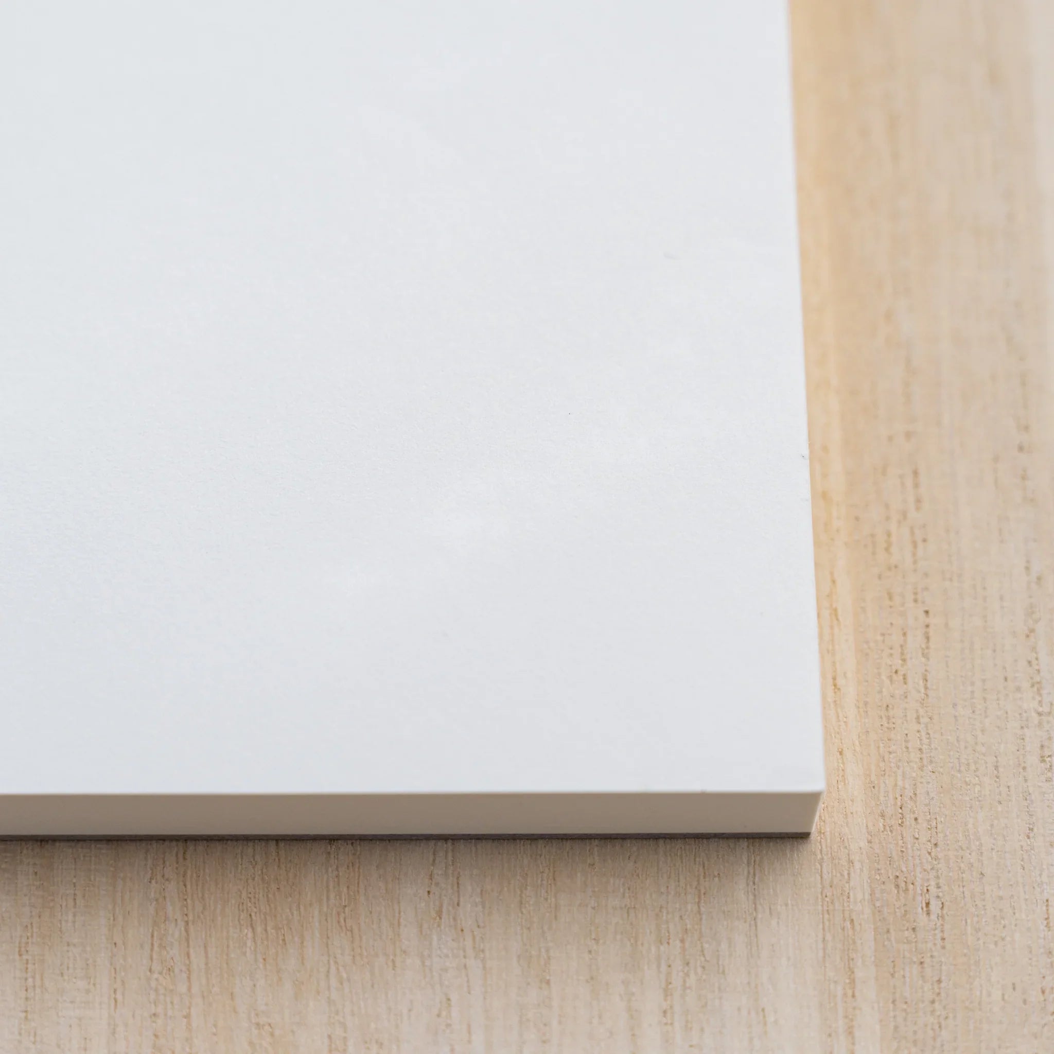 Close-up of Midori MD Paper Pad Cotton A4 lower edge showing the white top sheet and thin glued page block