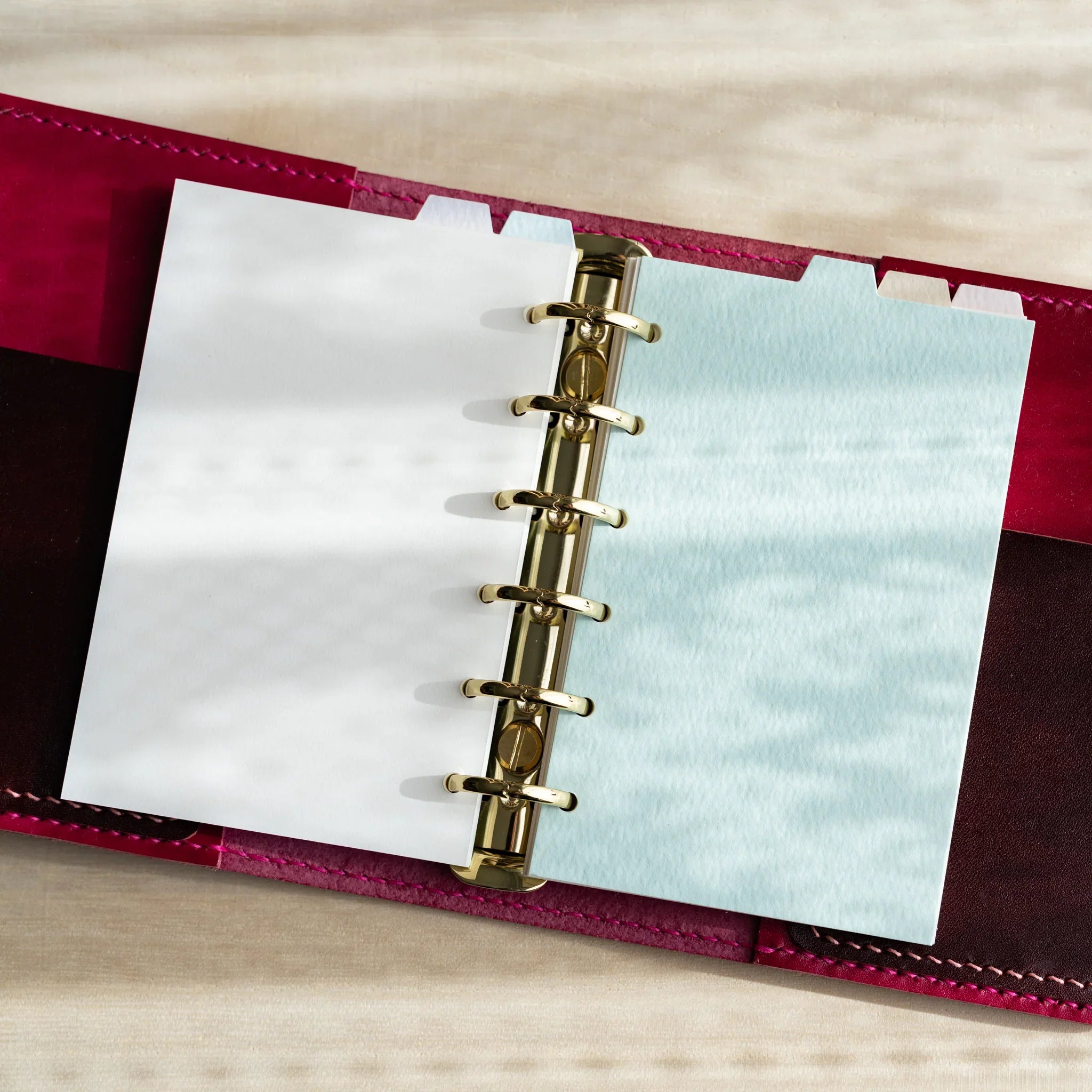 Japanese Stationery mini 6 planner open with gold ring binder showing white sheet on left and pastel blue index divider on right in red cover.