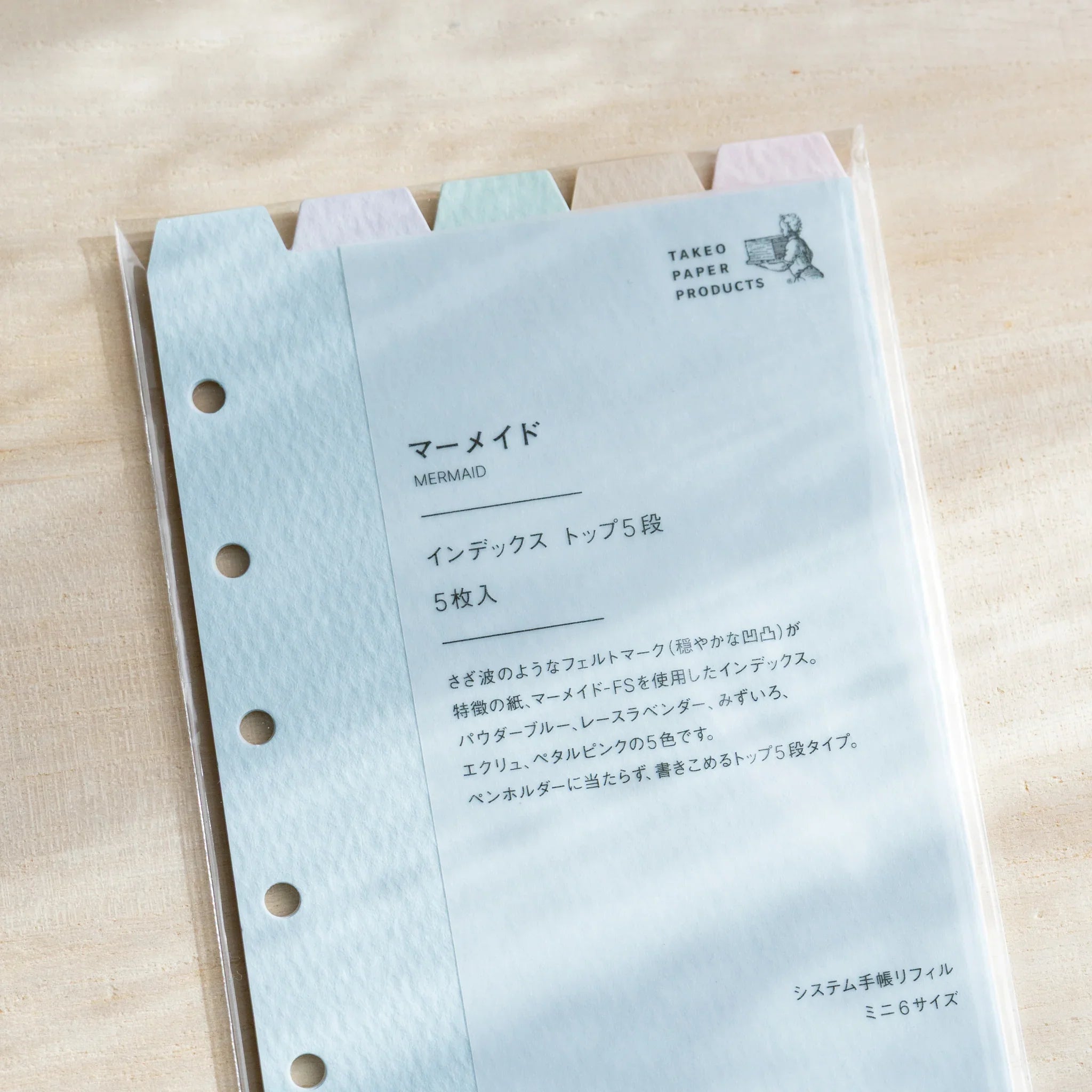 Japanese Stationery mermaid top-tab index dividers set in packaging with five pastel tabs visible on beige fabric.