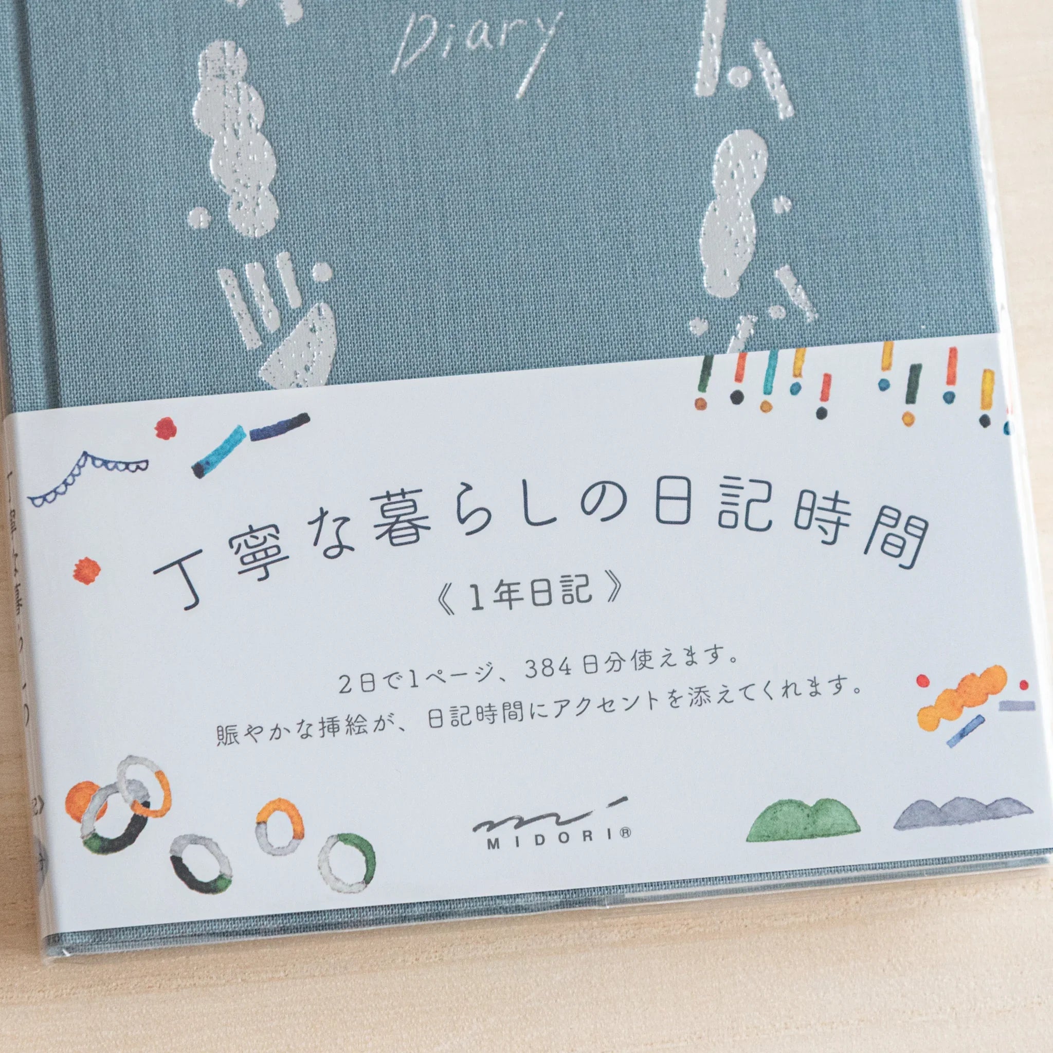 Front cover of Midori Japanese journal with outing design, blue fabric and Japanese band with colorful icons.