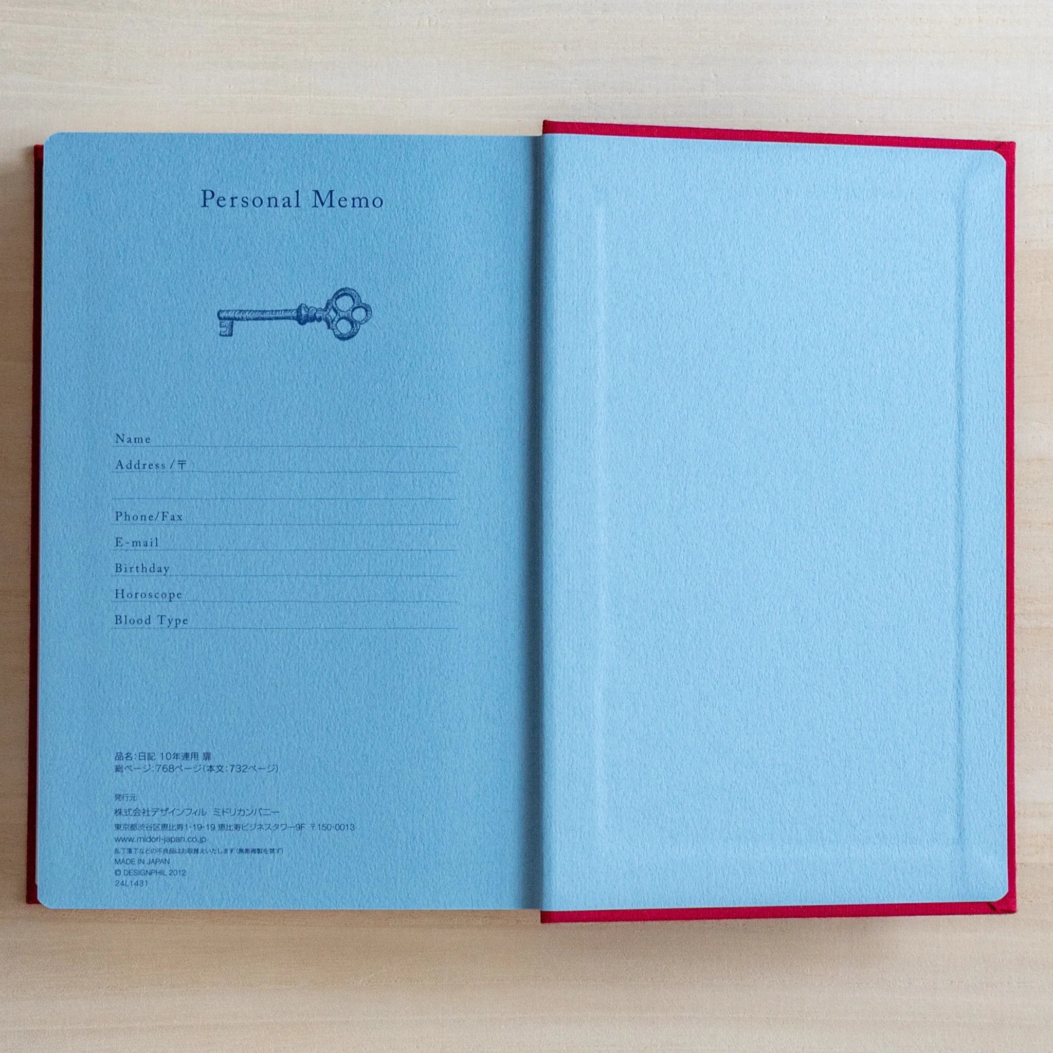 Open Midori Japanese journal 10-year diary gate design showing blue personal memo page with key illustration and blank page.