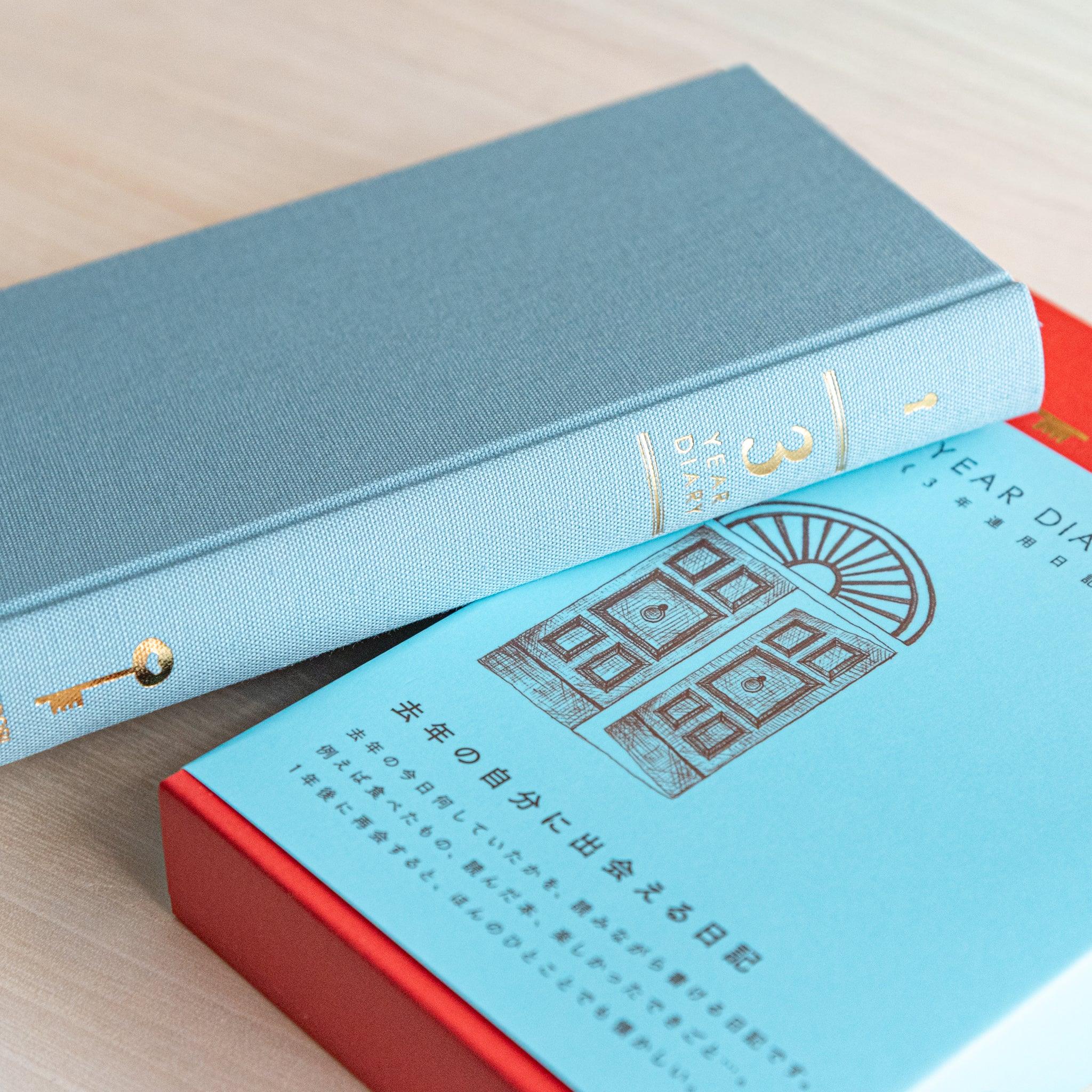 Side view of Midori Japanese journal 3 Year Diary Gate Design showing gold key on spine and red box below.