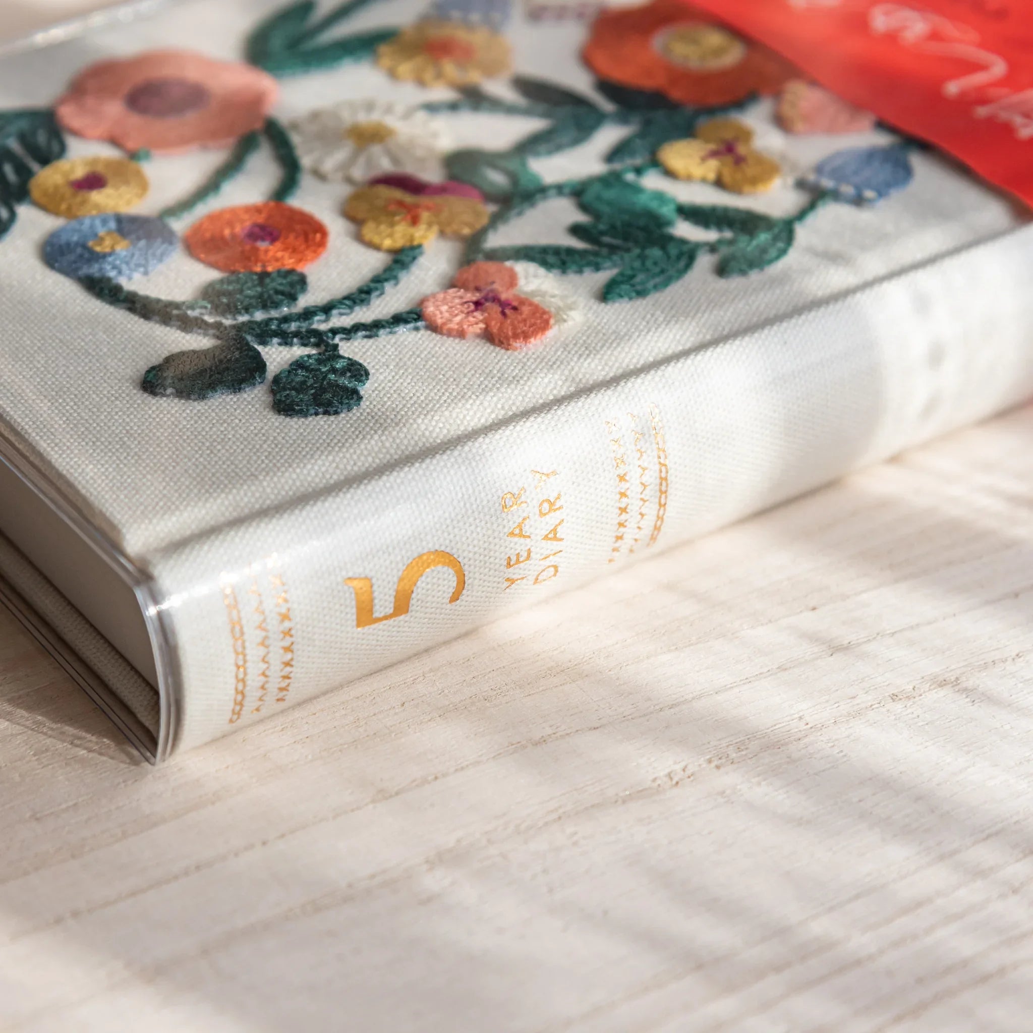 Midori 5-year journal, angled composition highlighting floral embroidery, Japanese stationery product with quality design and