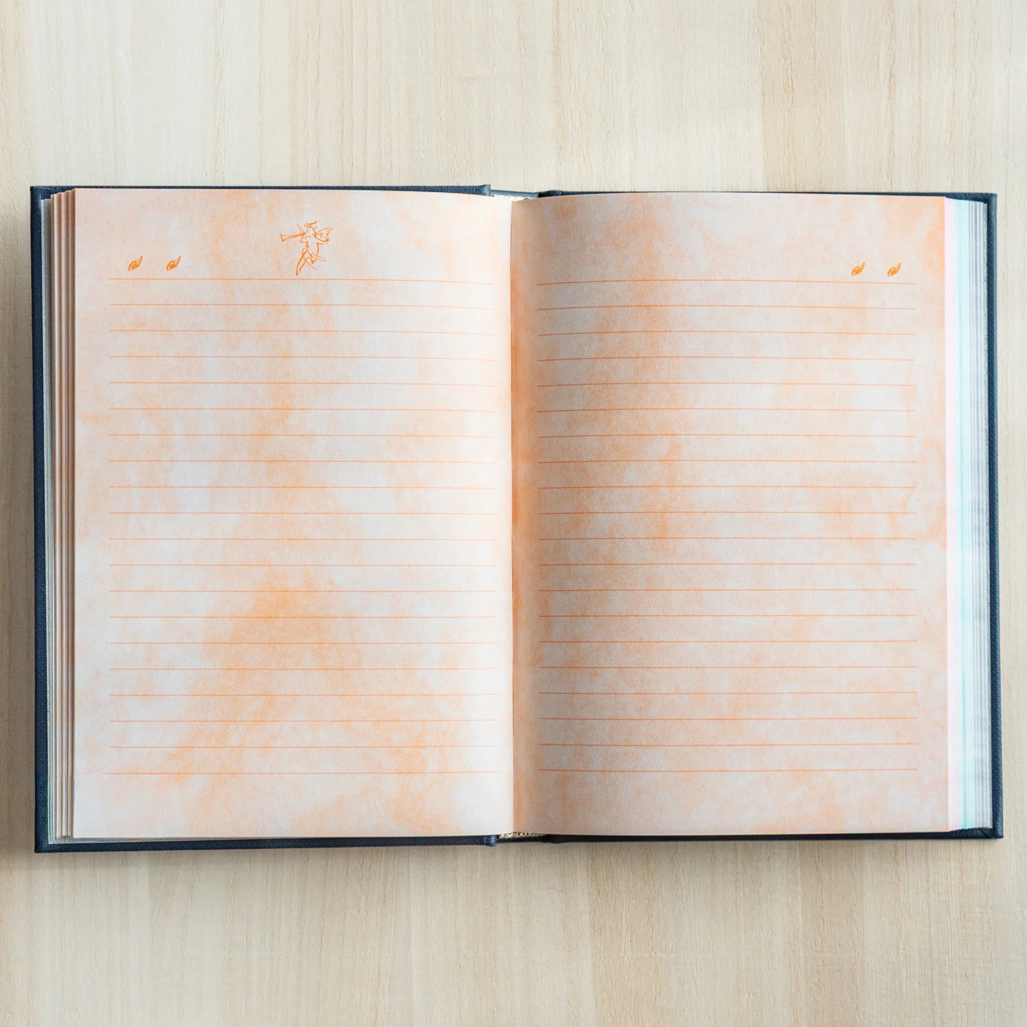 Open Midori Angel Motif Journal showing two lined pages with orange watercolor wash and tiny angel illustrations at top corners