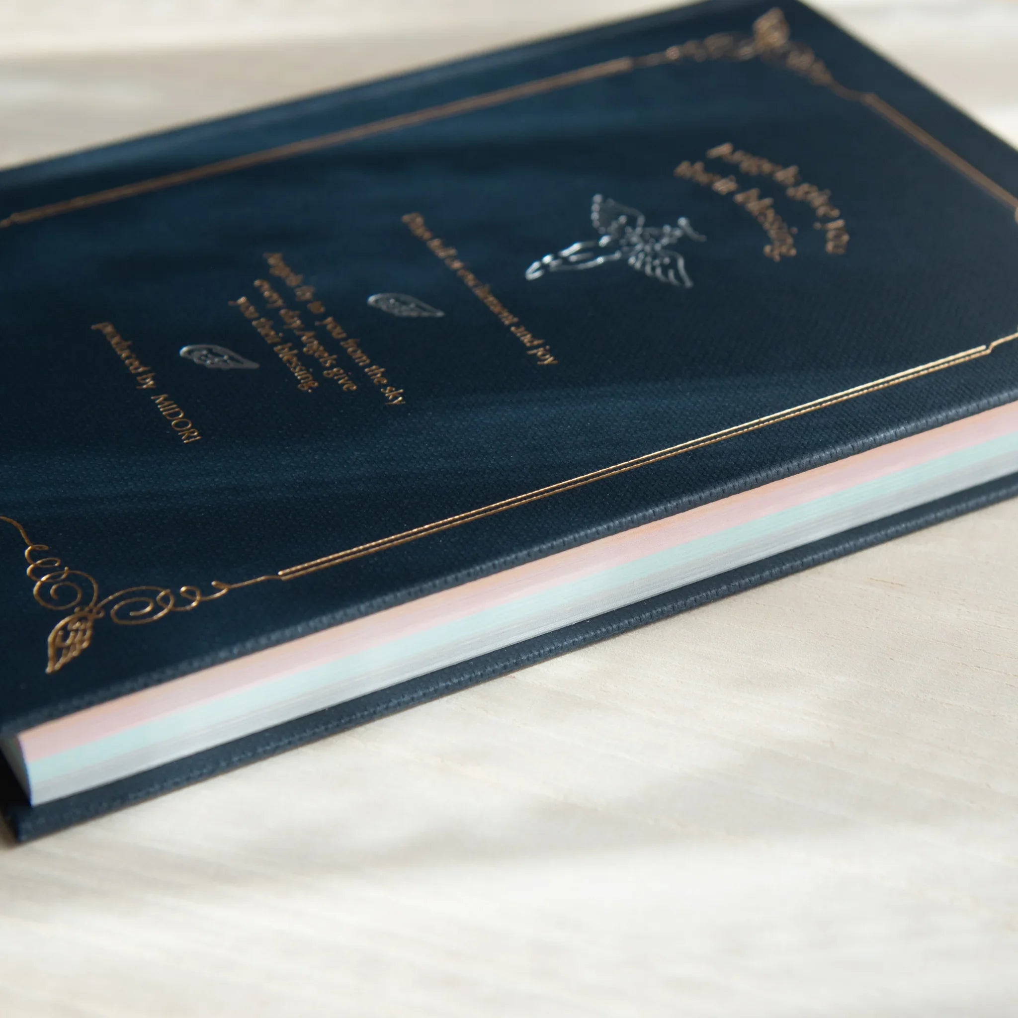 Notebook binding viewed at angle showing colored page edges in pink, white and light blue tones arranged vertically