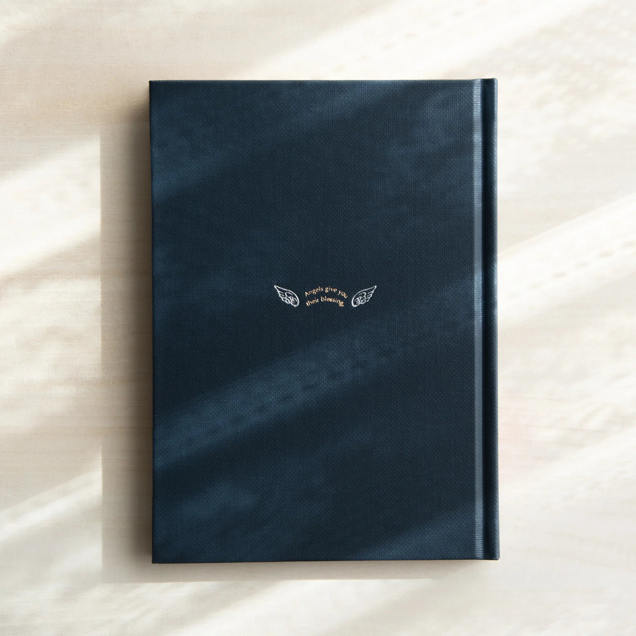 Open journal showing interior pages with printed angel motif pattern consistently on white writing surface paper