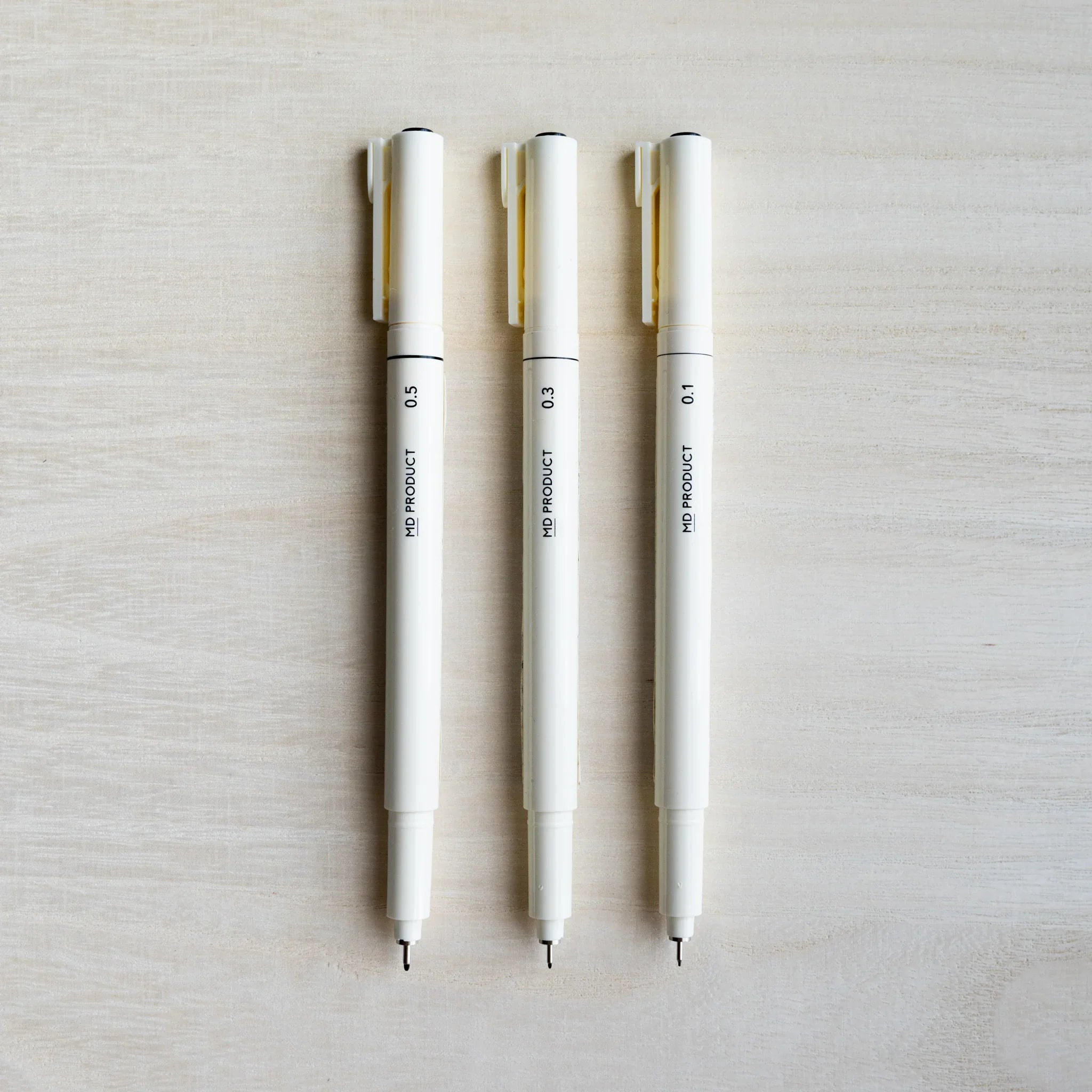 Three Midori MD Drawing Pens uncapped with caps posted, fine tips out, barrels marked 0.5, 0.3, and 0.1 mm