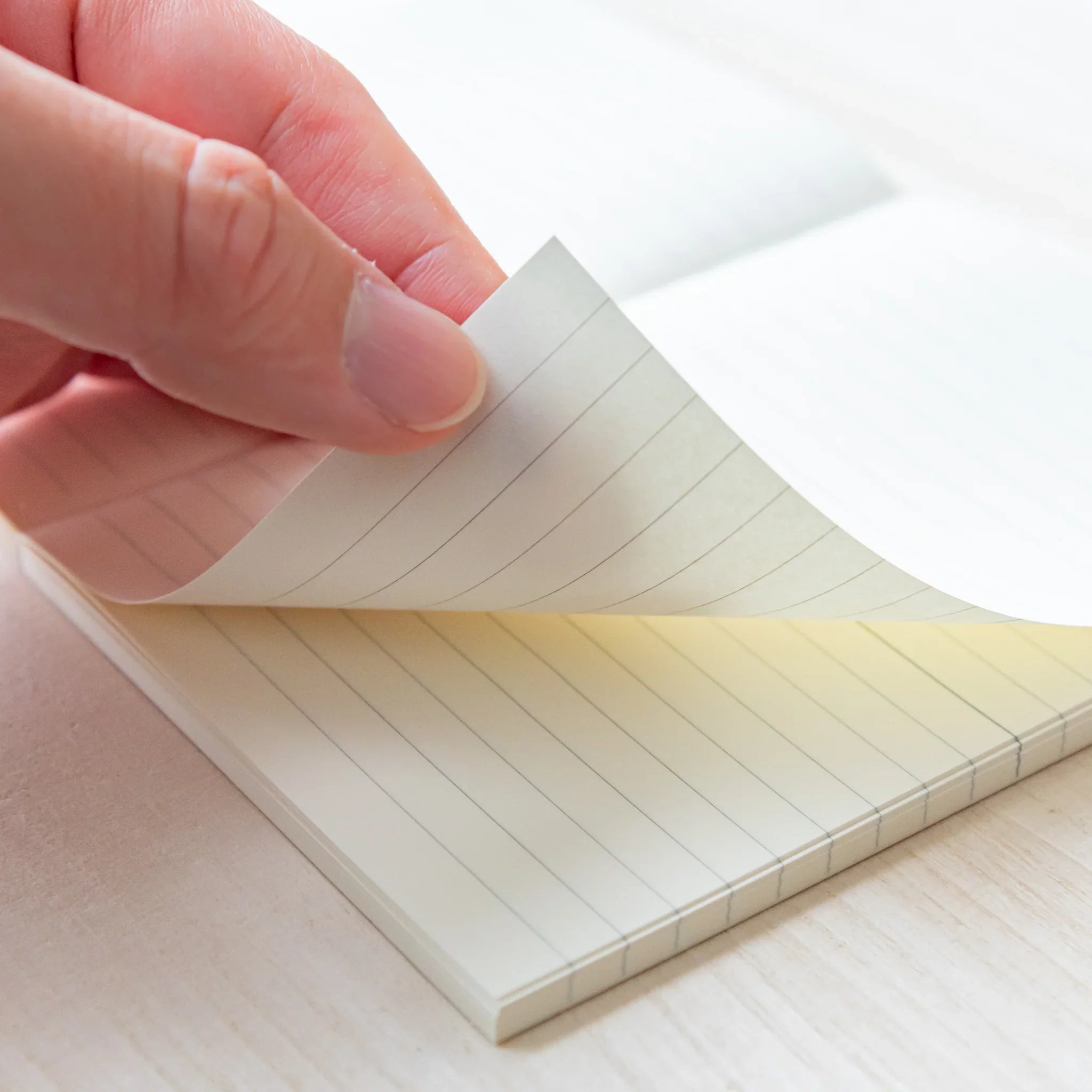 Japanese Notebook Midori MD A6 lined page being turned by hand, showing smooth cream paper.