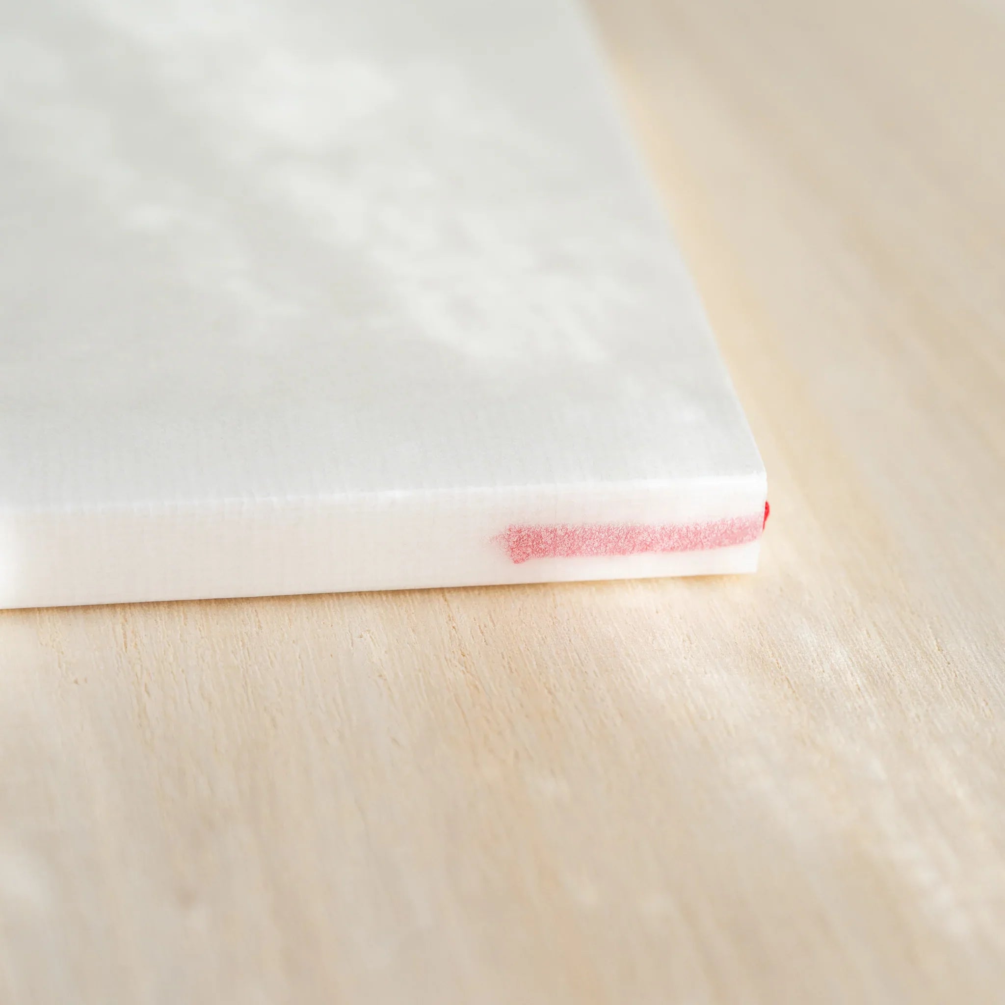 Midori MD Notebook A6 Blank side view, ivory page edges with red bookmark ribbon at bottom, glassine cover on top