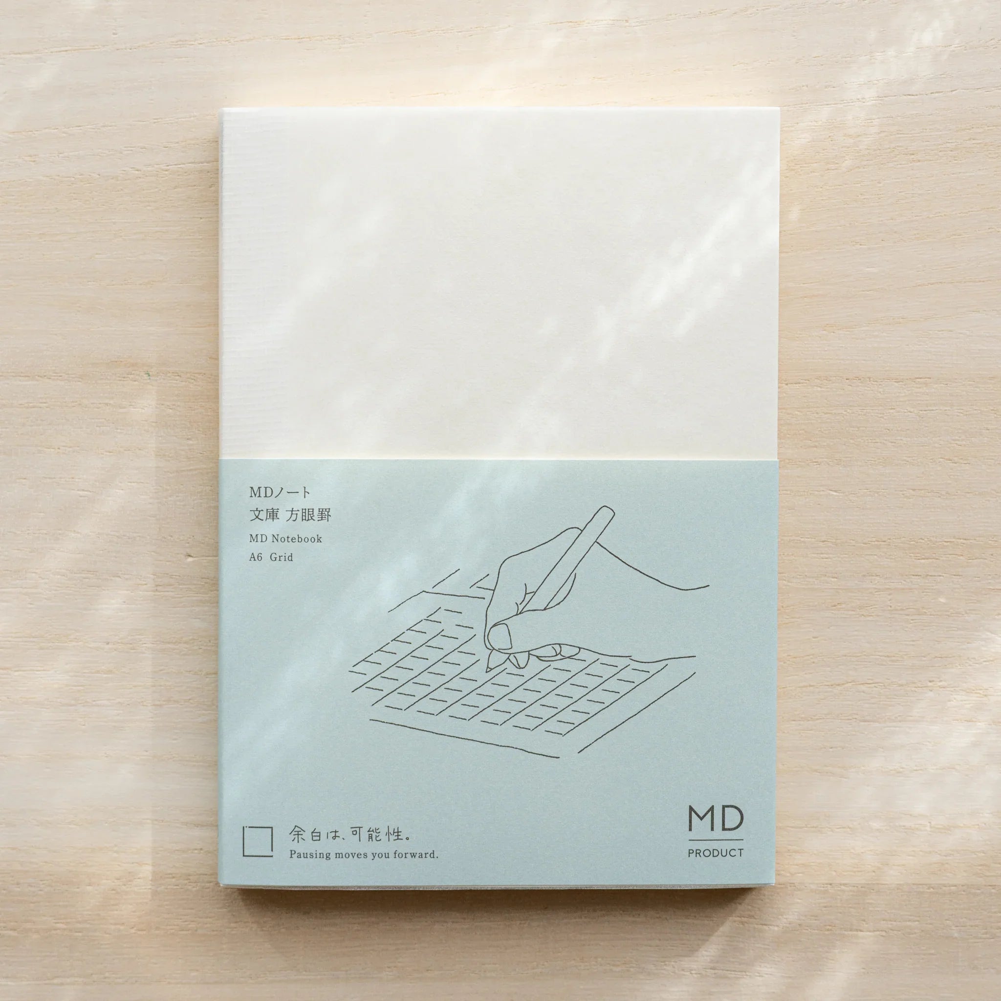 Midori MD Notebook A6 Grid with glassine cover, teal hand-writing illustration on grid, MD Product logo on front