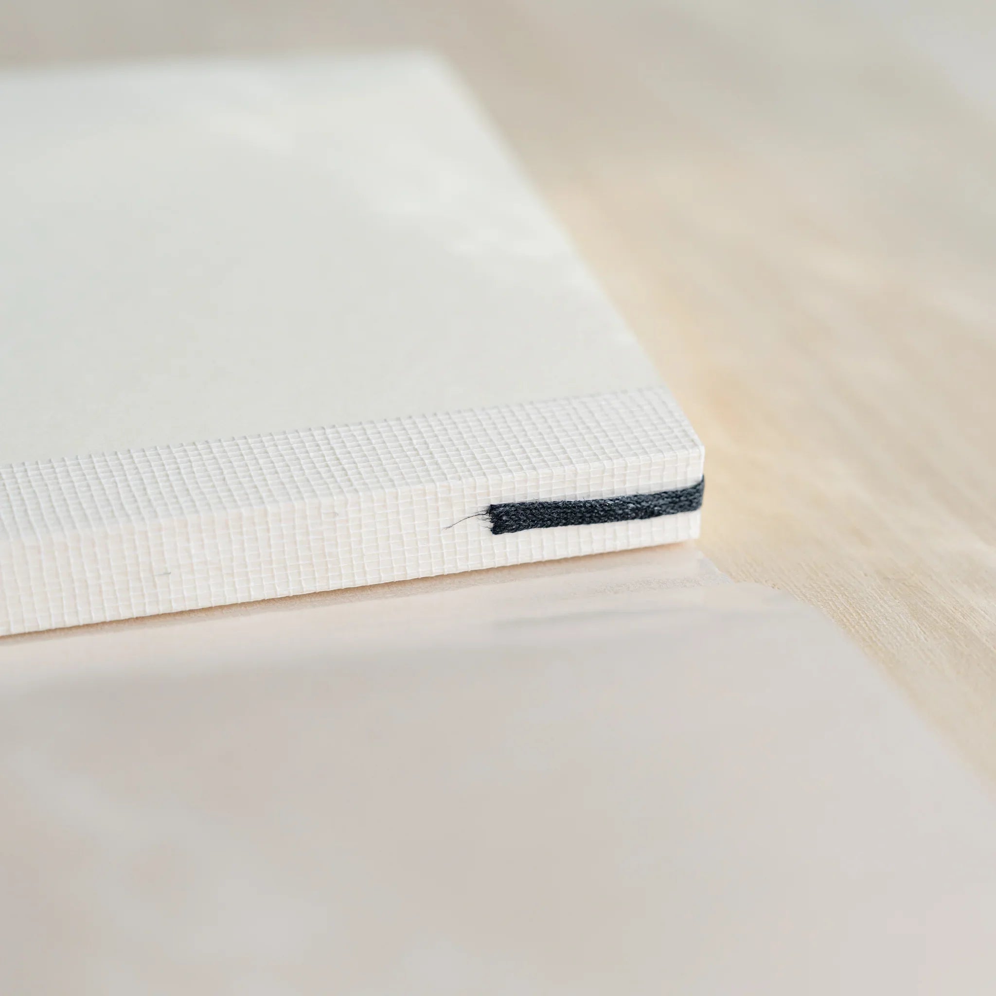 Midori MD Notebook A6 Grid spine close-up showing white thread-stitched binding with dark blue bookmark ribbon at bottom