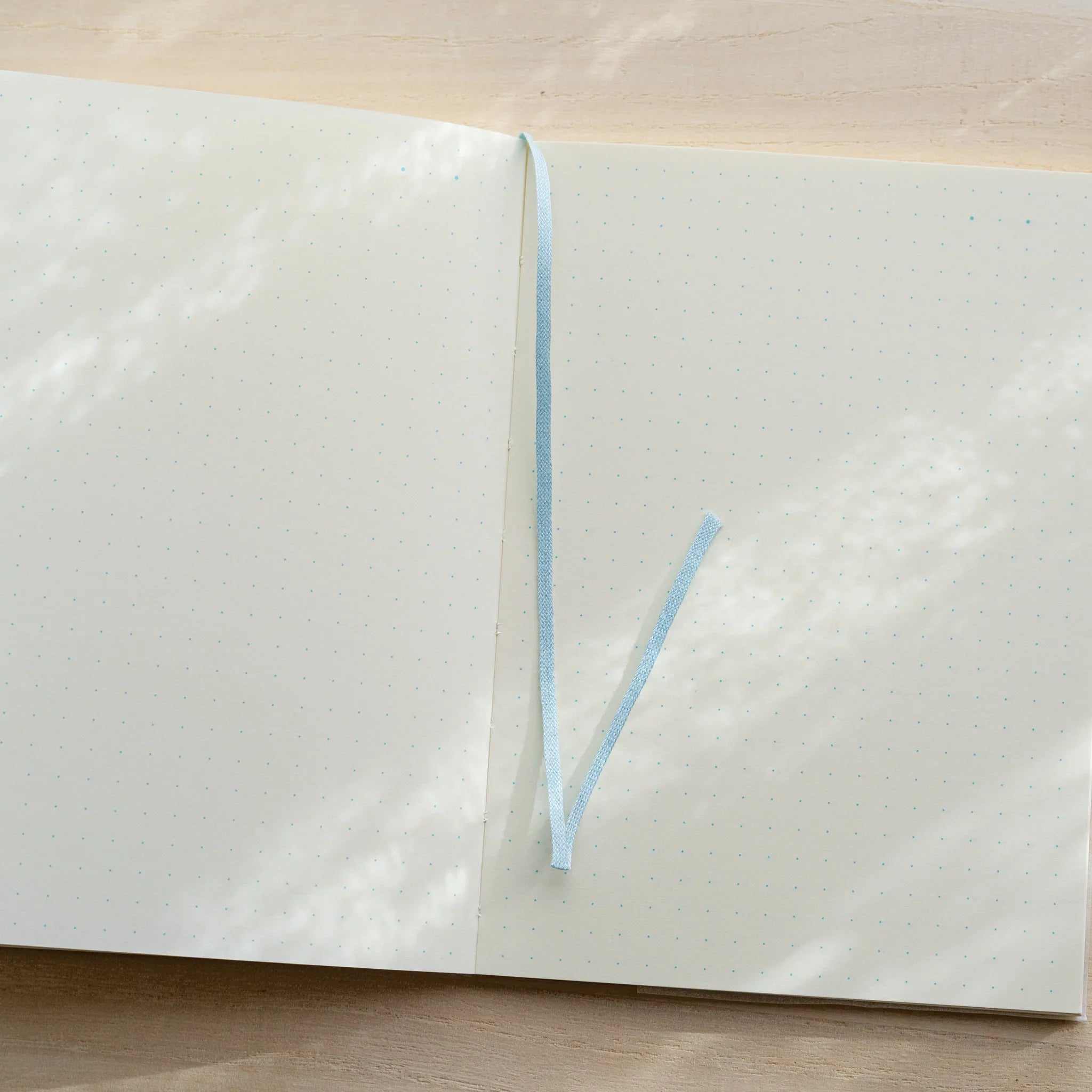 Midori MD Notebook A6 open to dot grid spread with light blue bookmark ribbon at center spine
