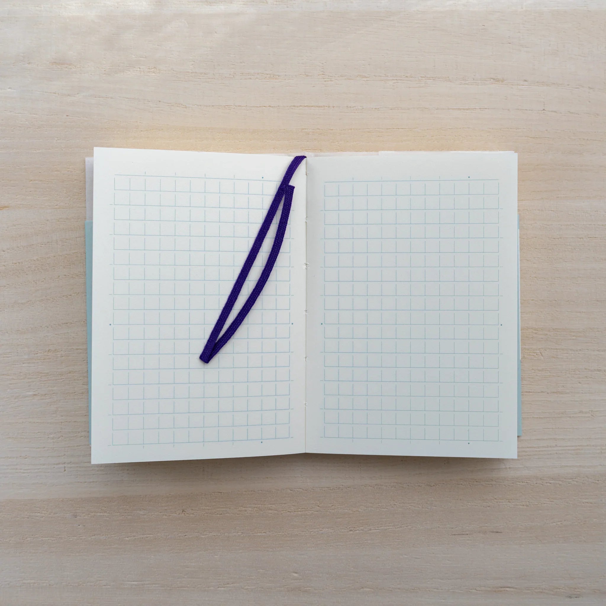 MD Notebook A7 opened to a dot grid spread with a blue pen resting on the page