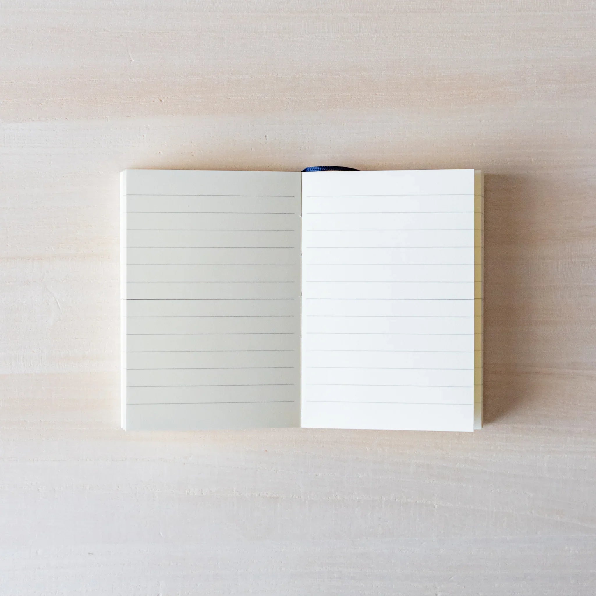 Japanese Notebook open lined pages of a Midori MD A7 notebook laid flat on a light wooden surface.