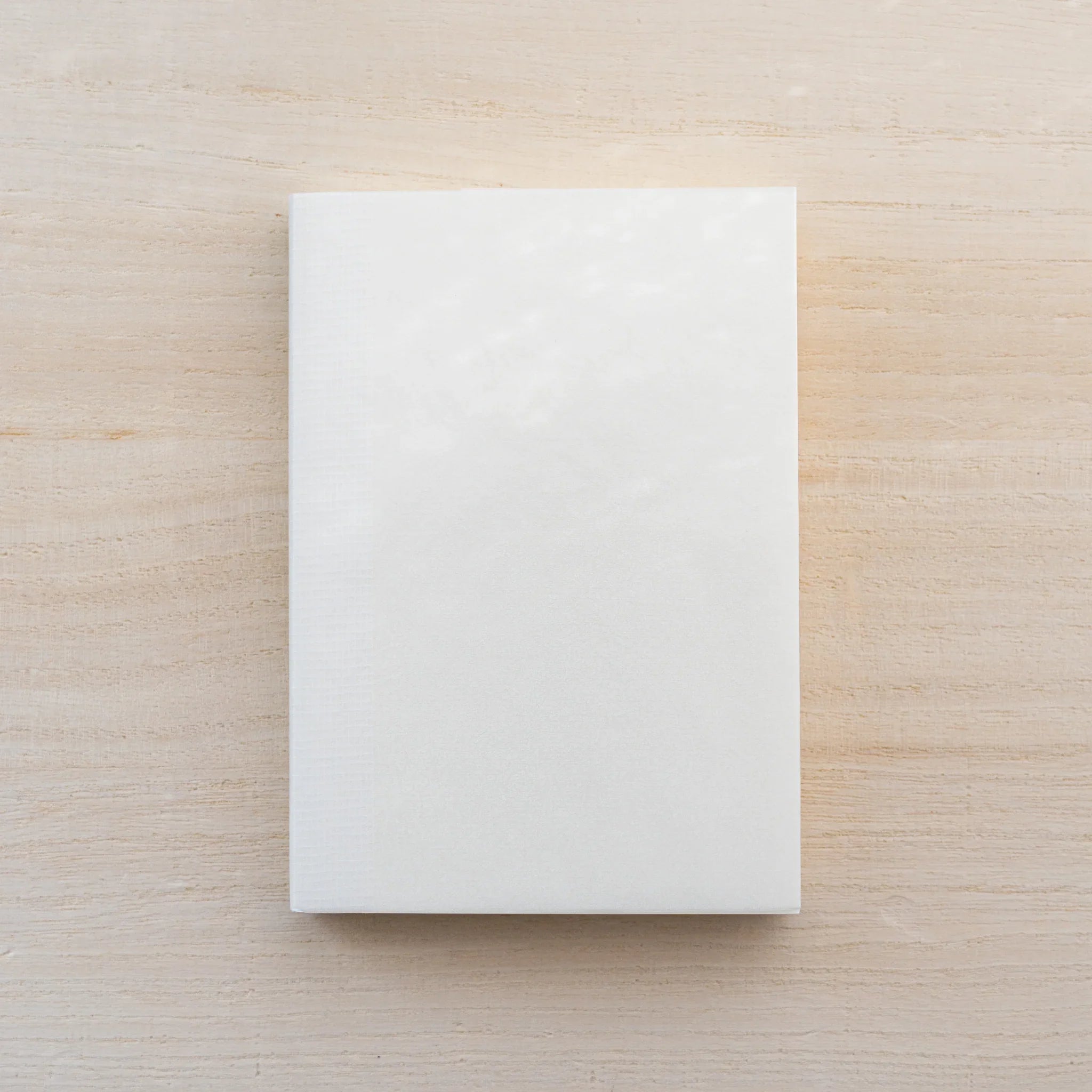 Cream MD Notebook A7, closed front cover on a wood surface