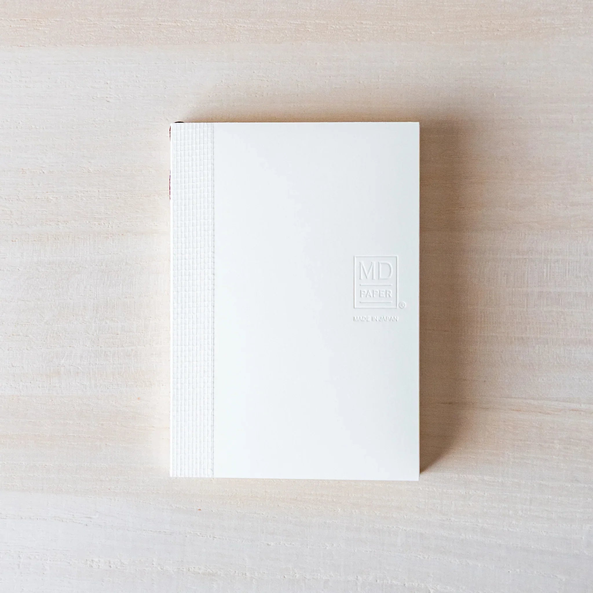 Japanese Notebook front view of a Midori MD A7 notebook with a minimalist white cover and embossed MD PAPER logo.