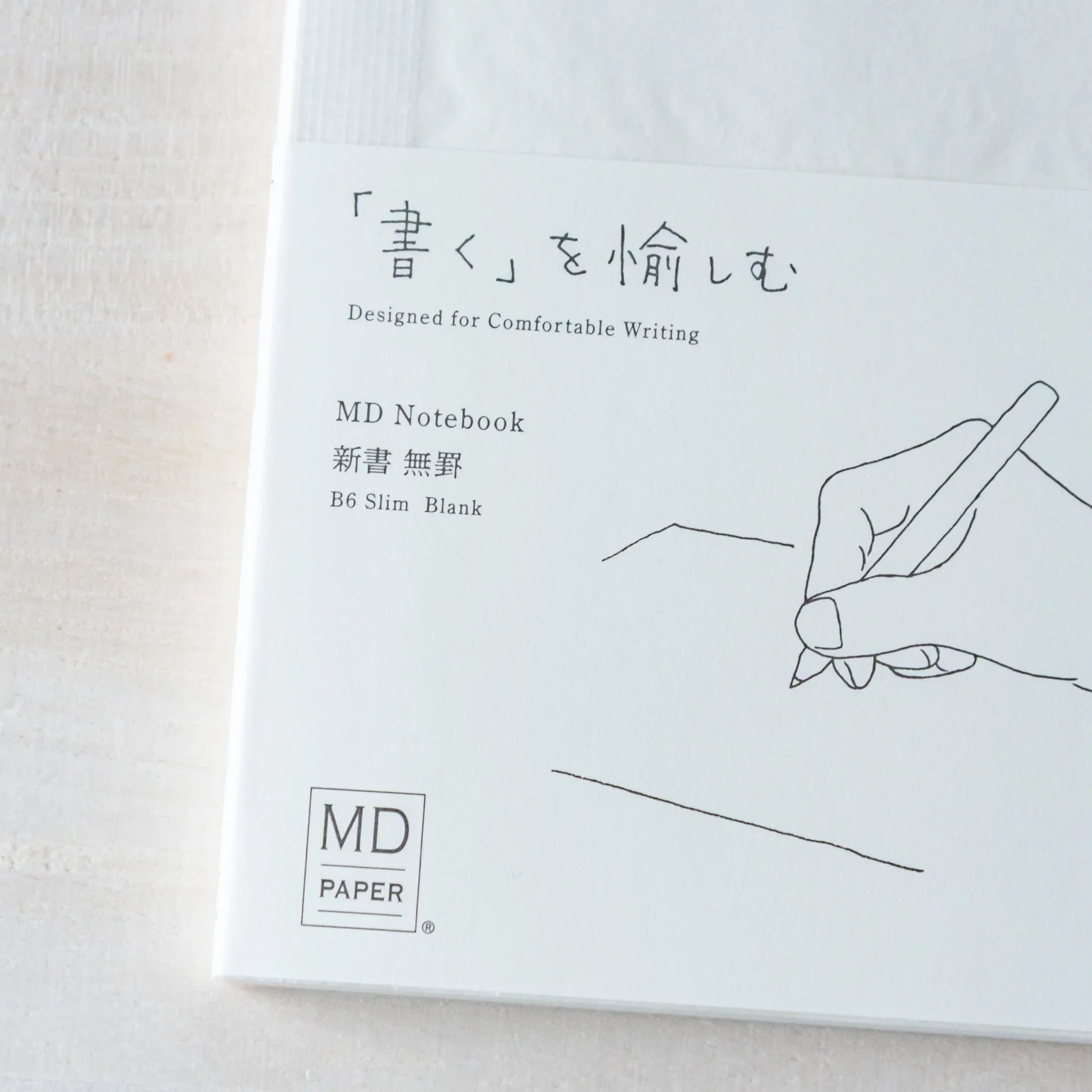 Japanese Notebook cover view of a Midori MD B6 notebook featuring a hand-drawing illustration, Japanese text, and logo.