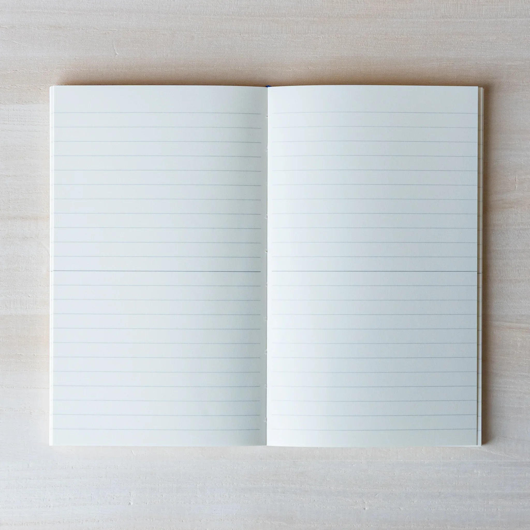 Japanese Notebook open lined pages of a Midori MD B6 notebook laid flat on a light wooden surface.