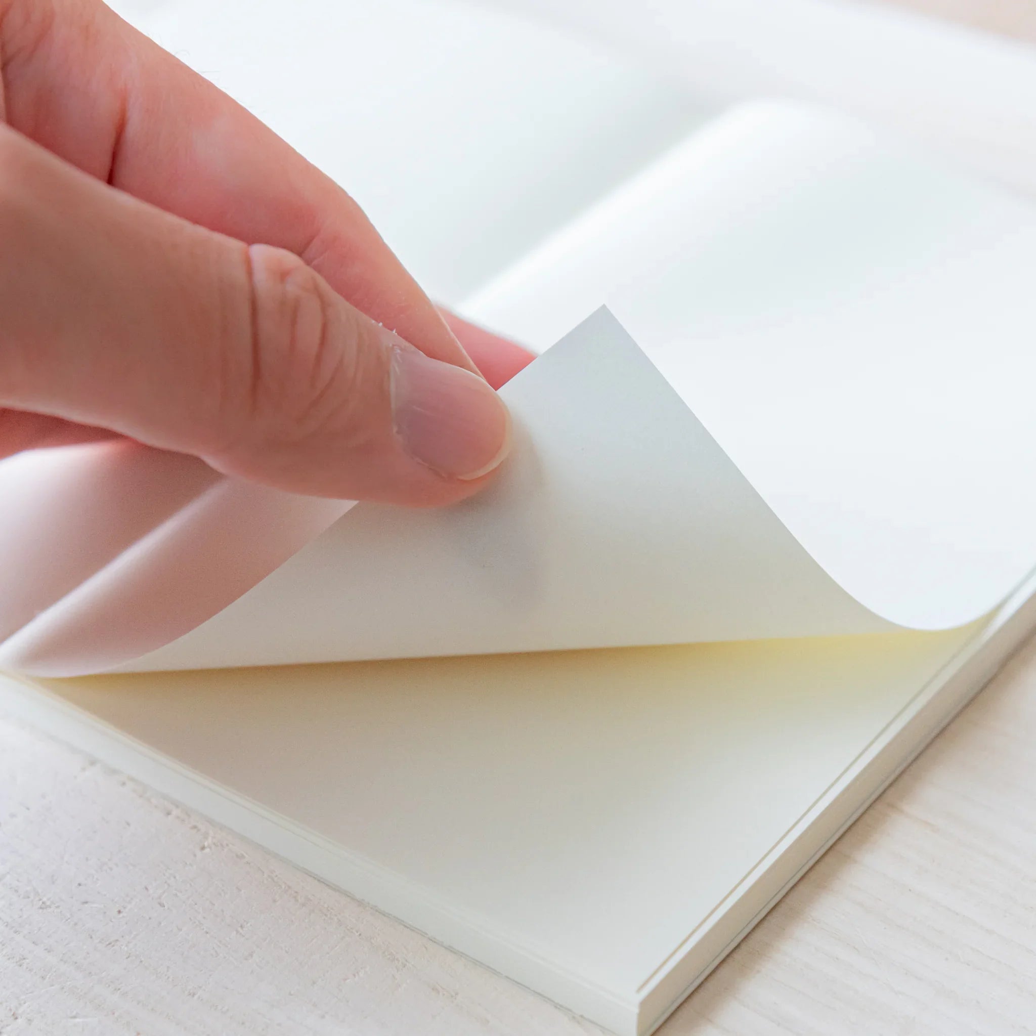 Japanese Notebook close-up of a Midori MD B6 notebook as a hand gently flips a cream-colored page, showing smooth MD Paper.