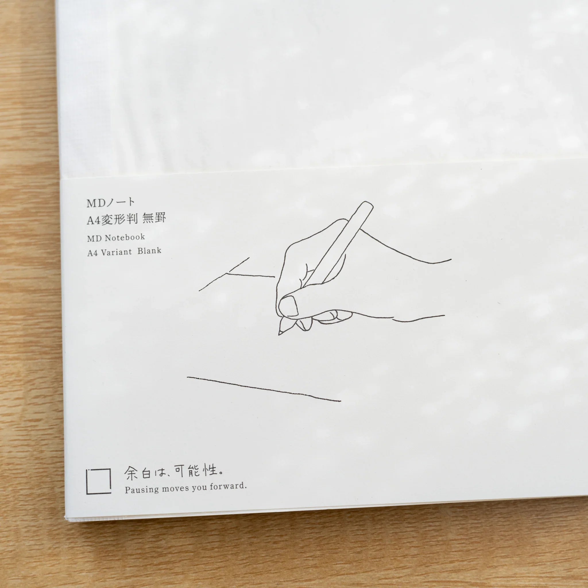 Close-up of Midori MD Notebook A4 Variant paper belly band, line drawing of a writing hand with Japanese and English title