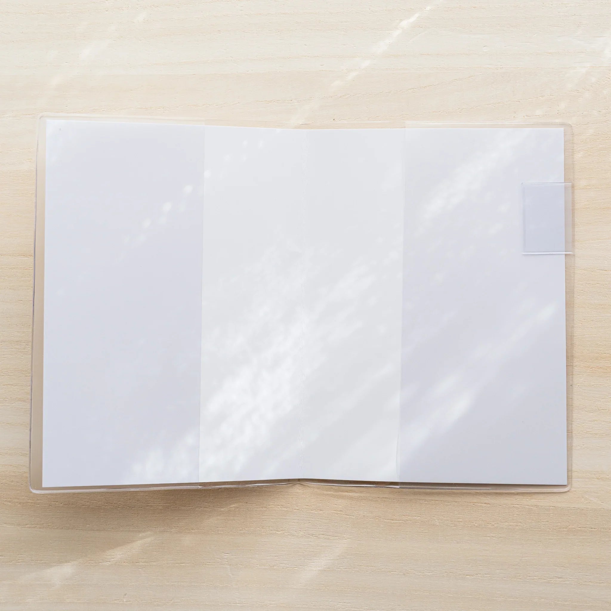 Midori MD Notebook A5 open flat inside clear PVC cover, blank white spread pages with white bookmark tab on right side