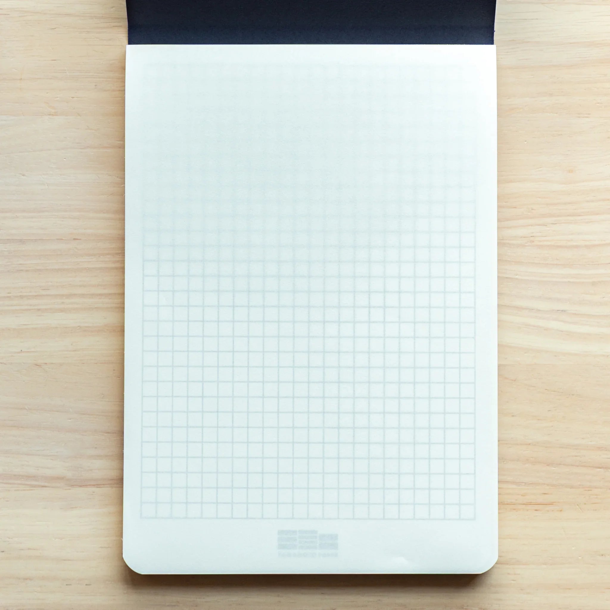 Japanese Paper Writing Pad A5 showing faint grid lines visible beneath translucent Bank Paper sheet for structured notes.