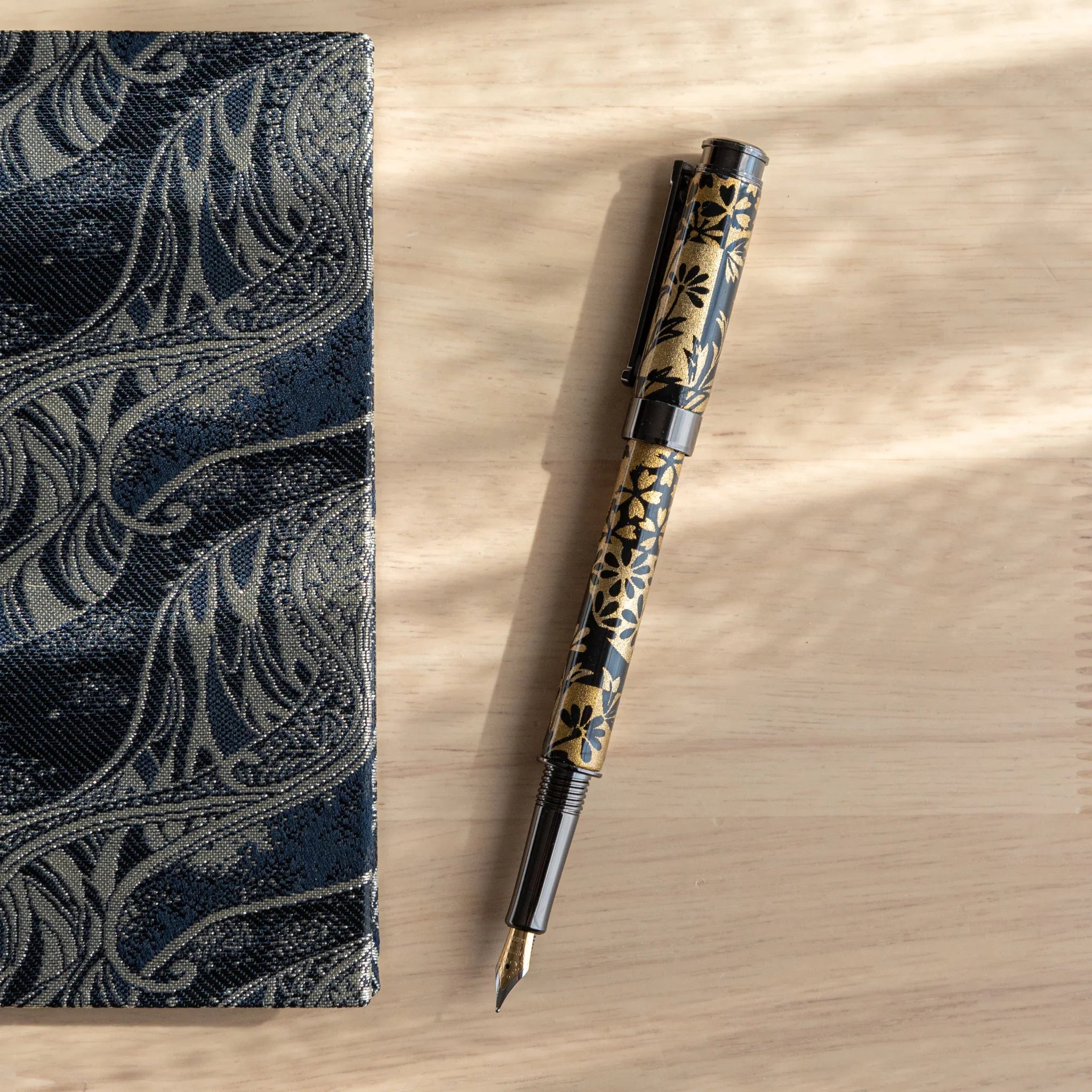 Fountain pen barrel section showing autumn grass botanical motif with gold accents on Mino washi paper wrapper