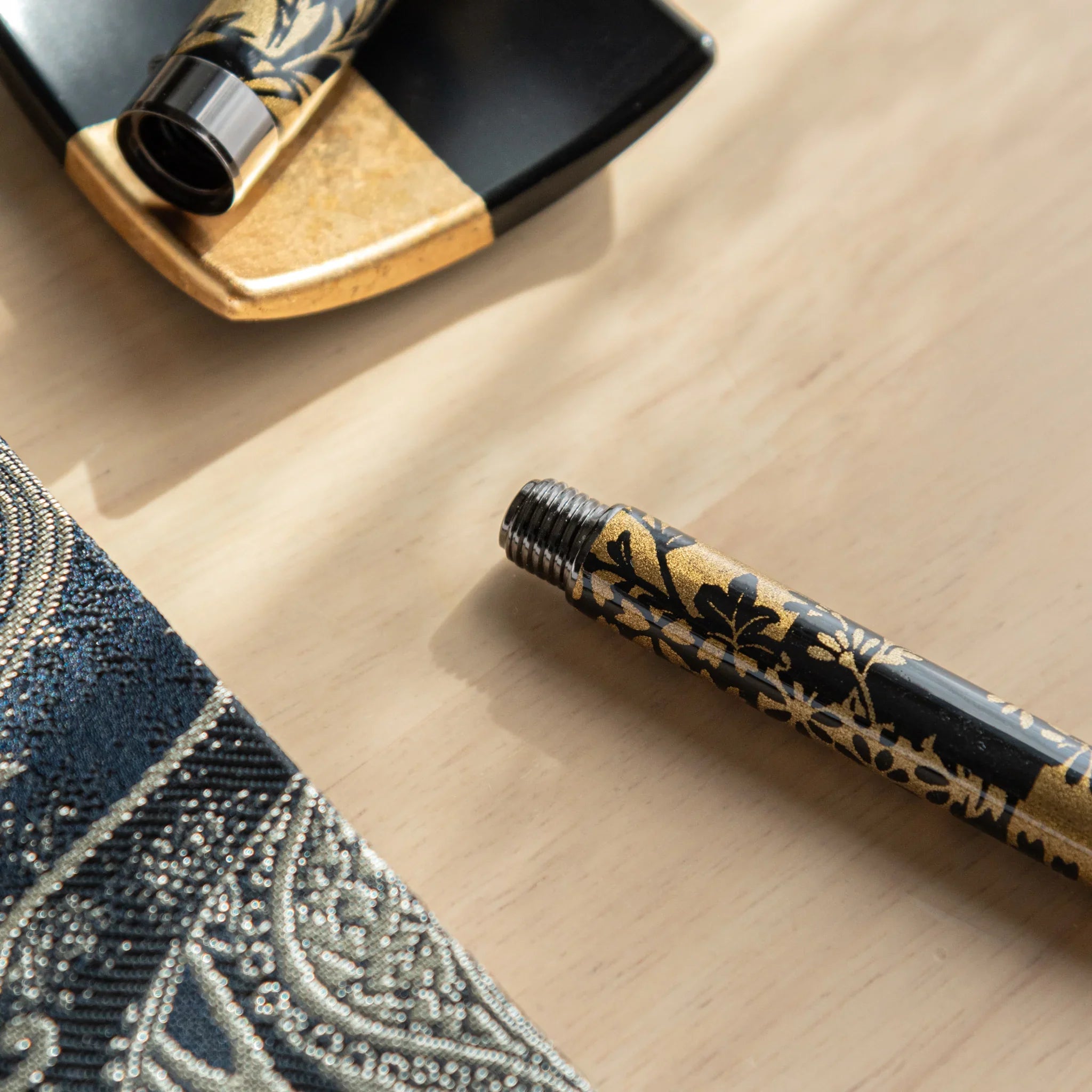 Black and gold fountain pen displaying golden autumn grass botanical pattern on black background Mino washi nib