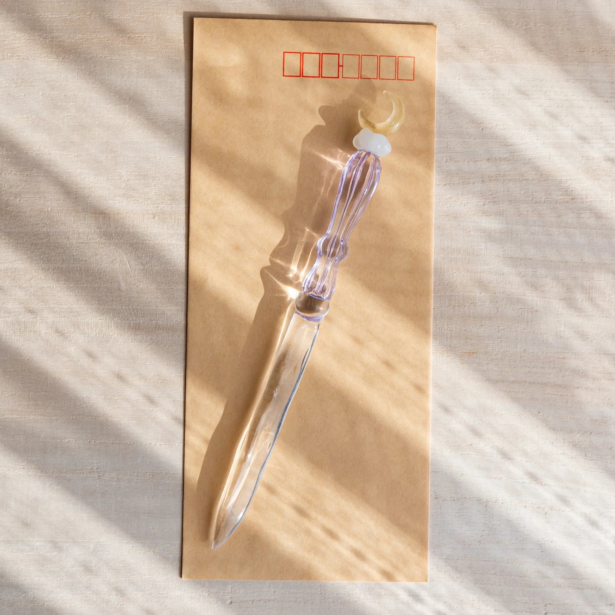 Moonlit cloud glass letter opener with lavender tint shown in composition displayed in detail product composition view
