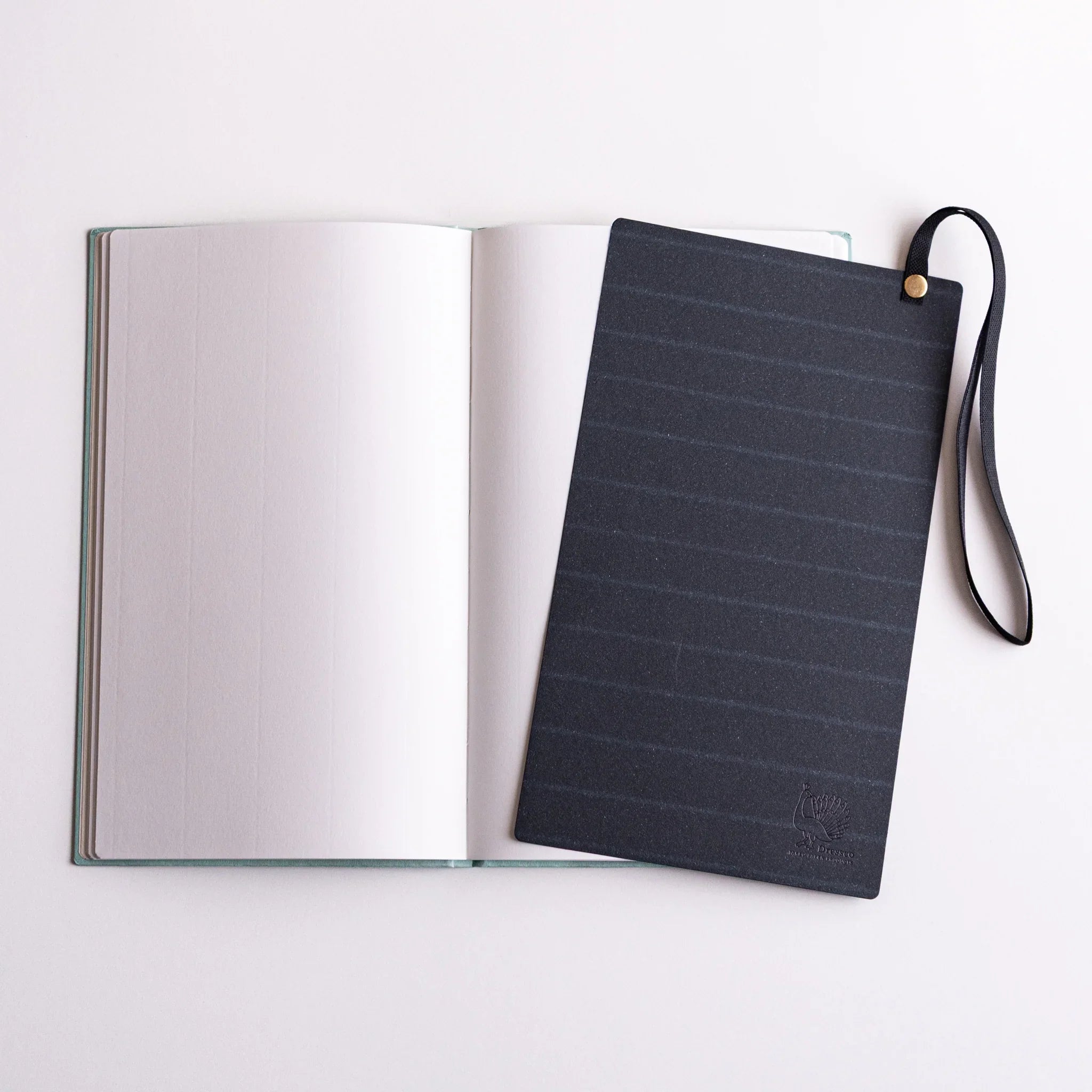 Navy band with strap on open notebook; multi-use accessory for Dressco B6, serves as closure, bookmark and writing board.