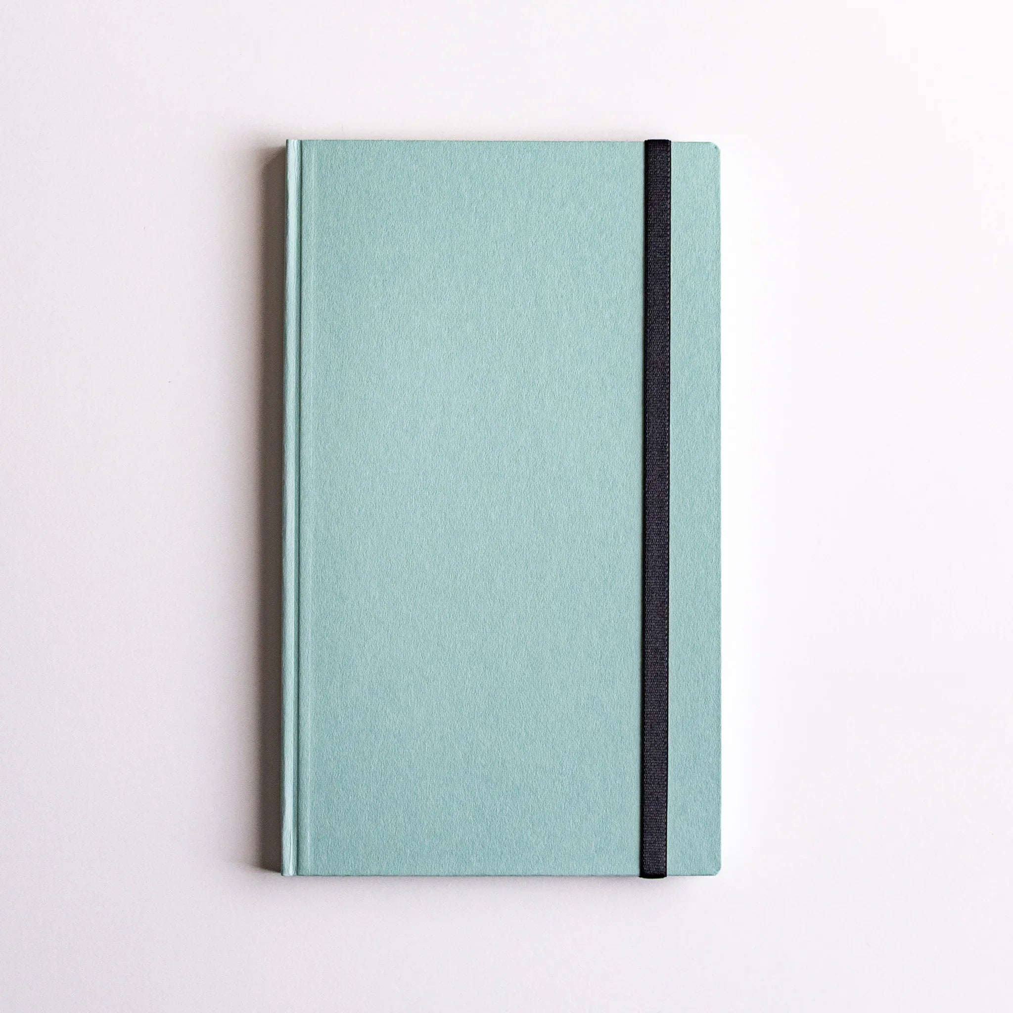 Closed mint green notebook with Dressco Sebiro Navy Blue bookmark band strap loop visible, showing secure closure.