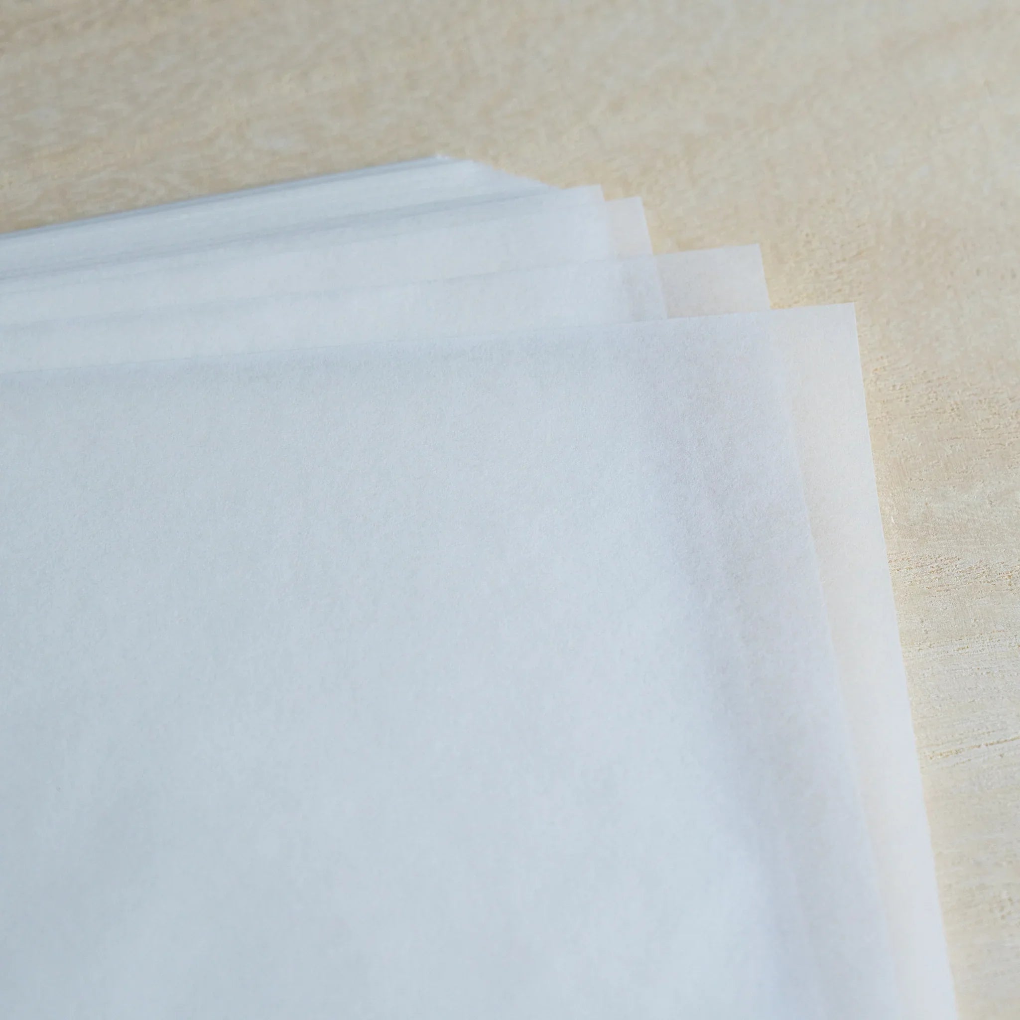 Loose sheets of MVP Onion Skin paper fanned out on light wood, thin translucent white sheets with layered edges