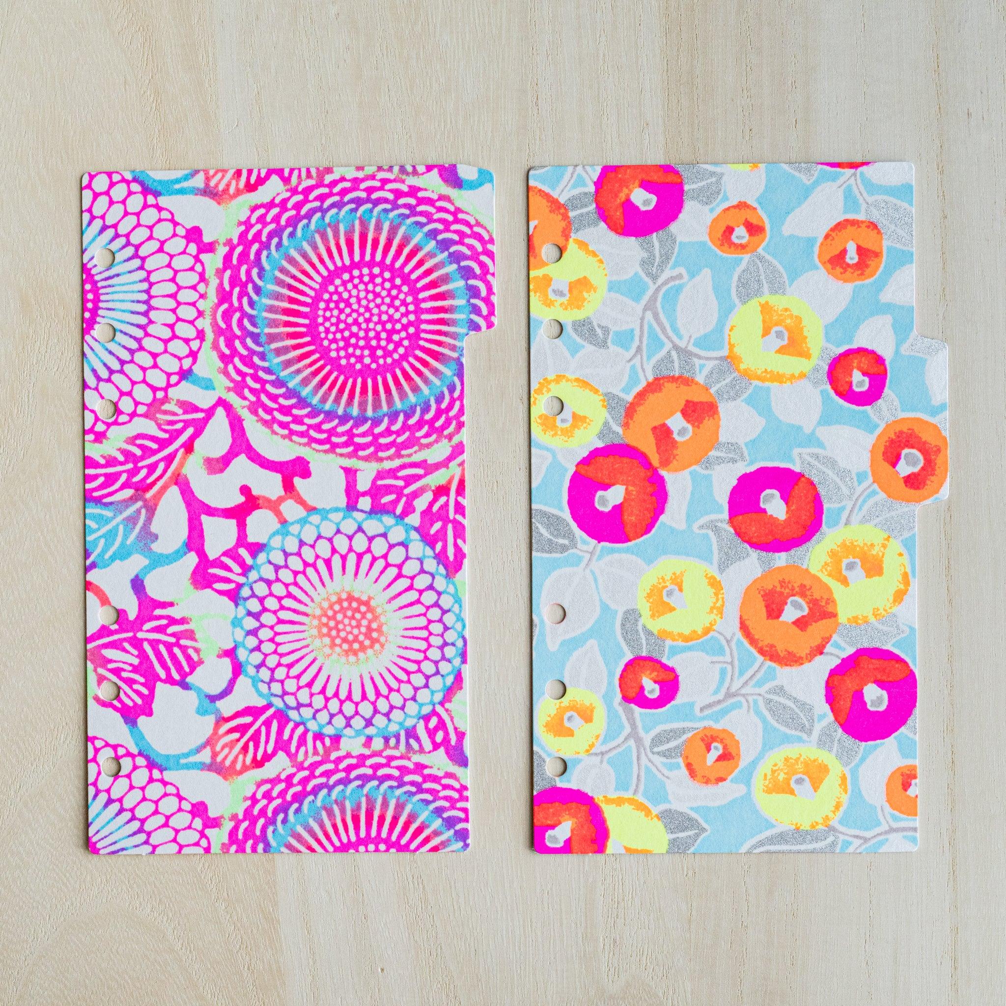 Two neon index dividers side by side, pink chrysanthemum print and light blue camellia print on washi